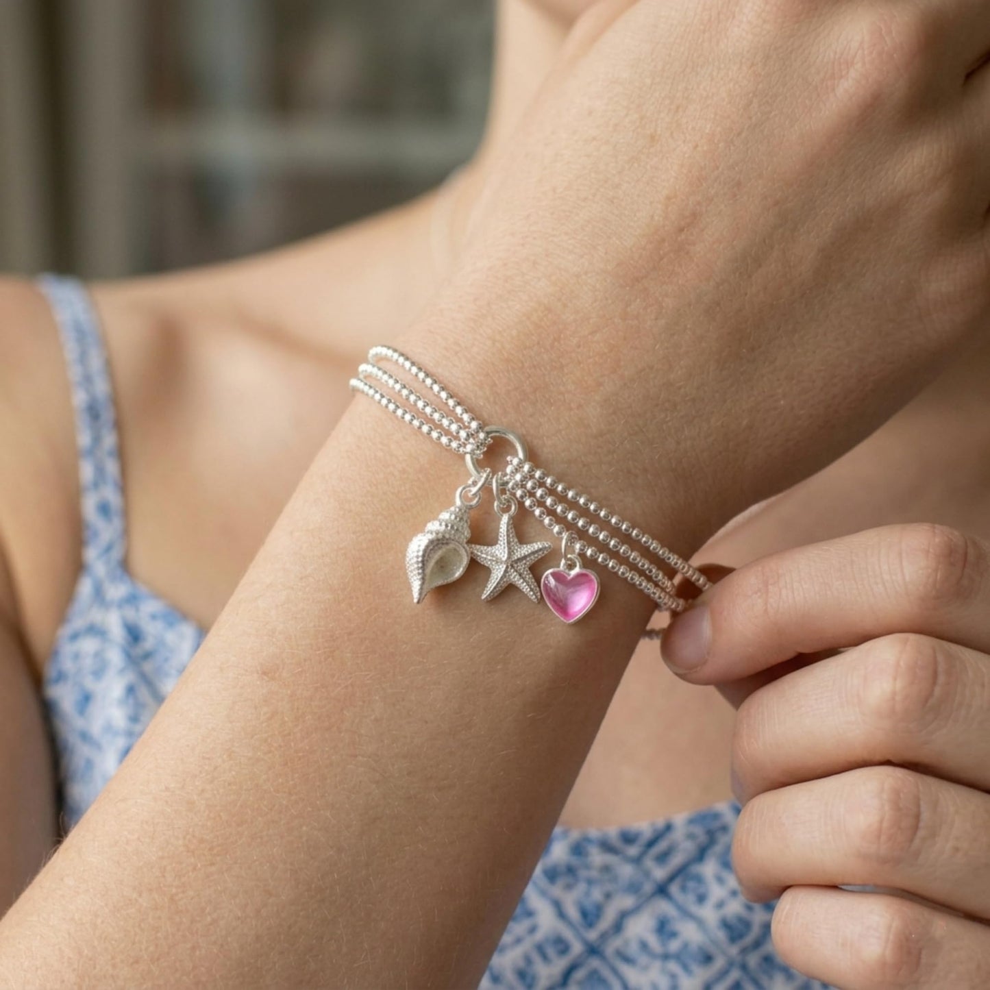 Silver snail shell charm on a multi-chain bracelet with starfish and heart accents
