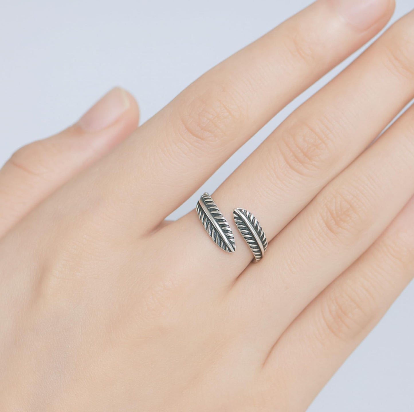 Oxidised feather-and-leaf ring on hand, two feather-ridged leaf bands