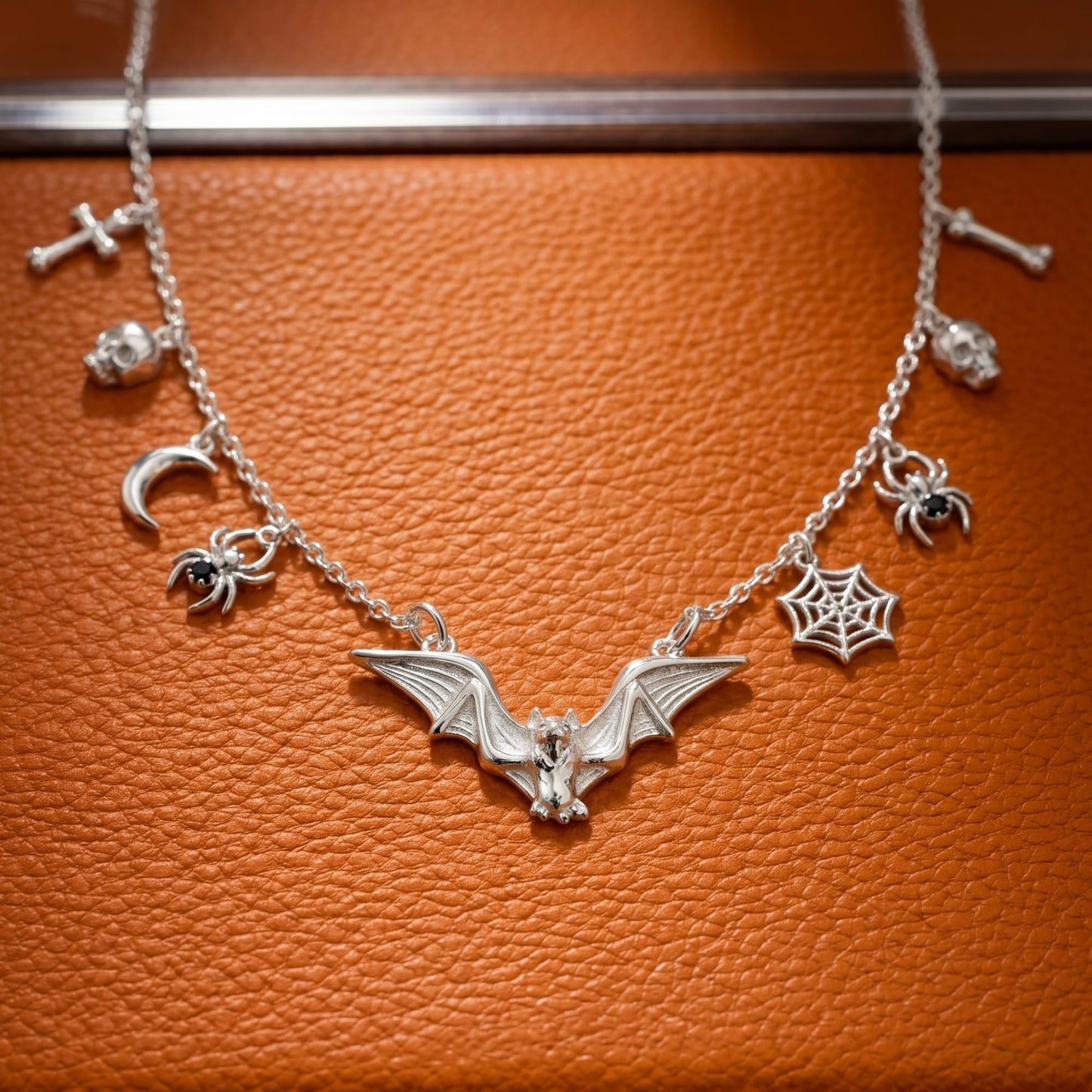 Silver-tone gothic bat necklace featuring bat wing charm, web charm, and small crosses