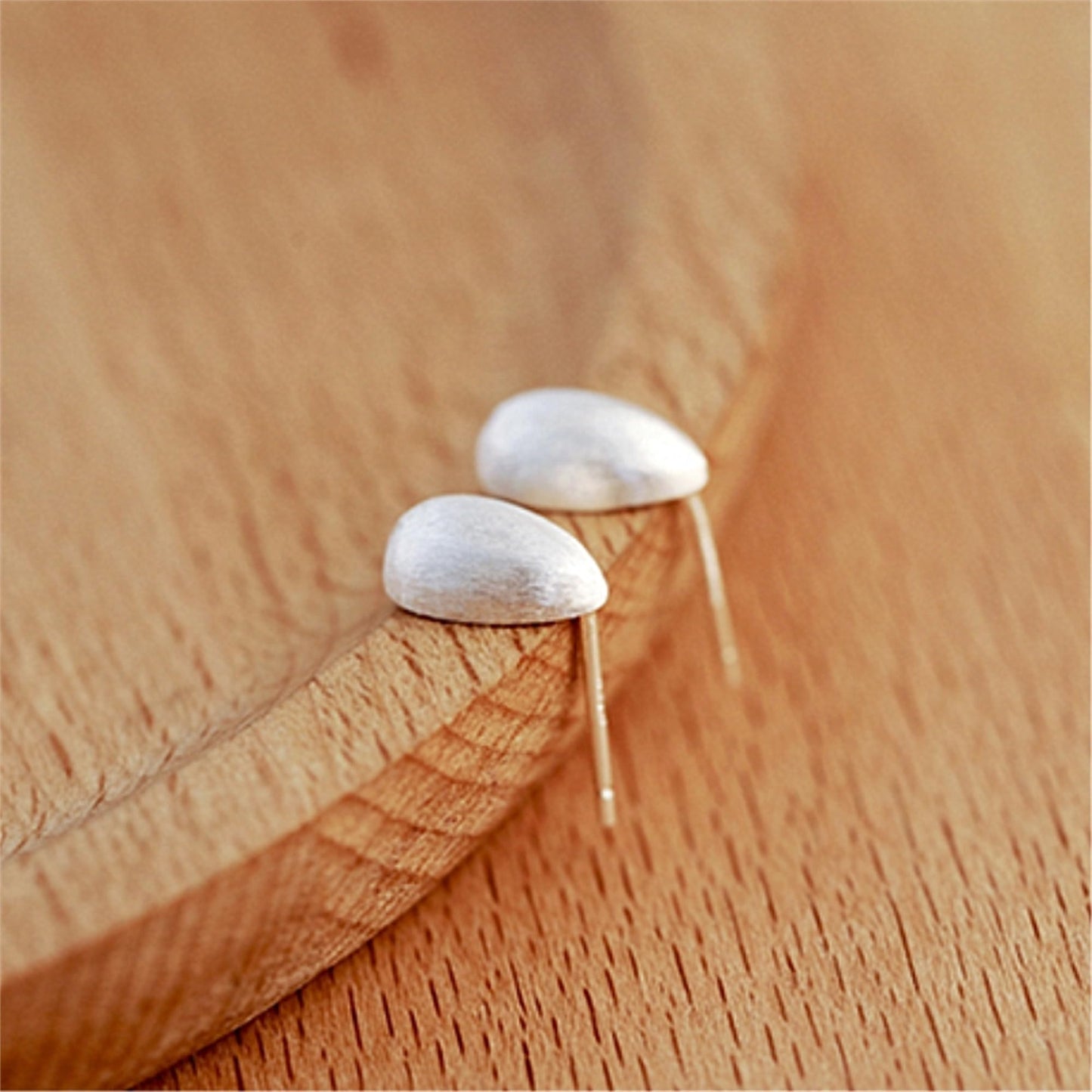 Teardrop stud earrings with silver-toned posts, brushed finish on wood