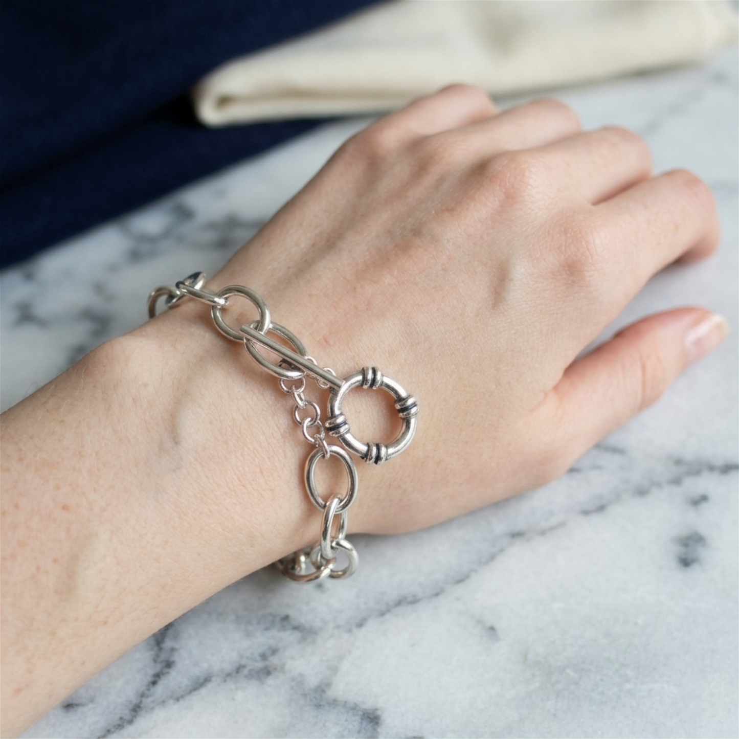 Oxidised linked T-bar bracelet on hand with oval links and ring charm