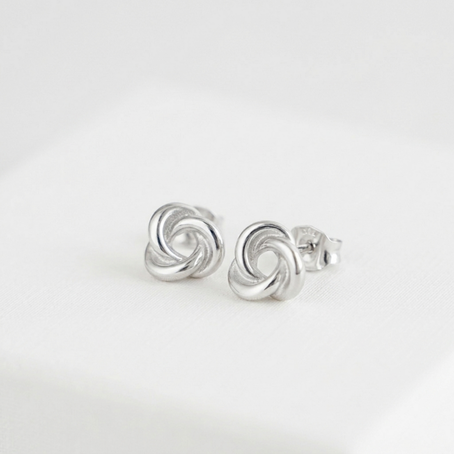 Silver knot stud earrings with butterfly backs, circular swirl detail
