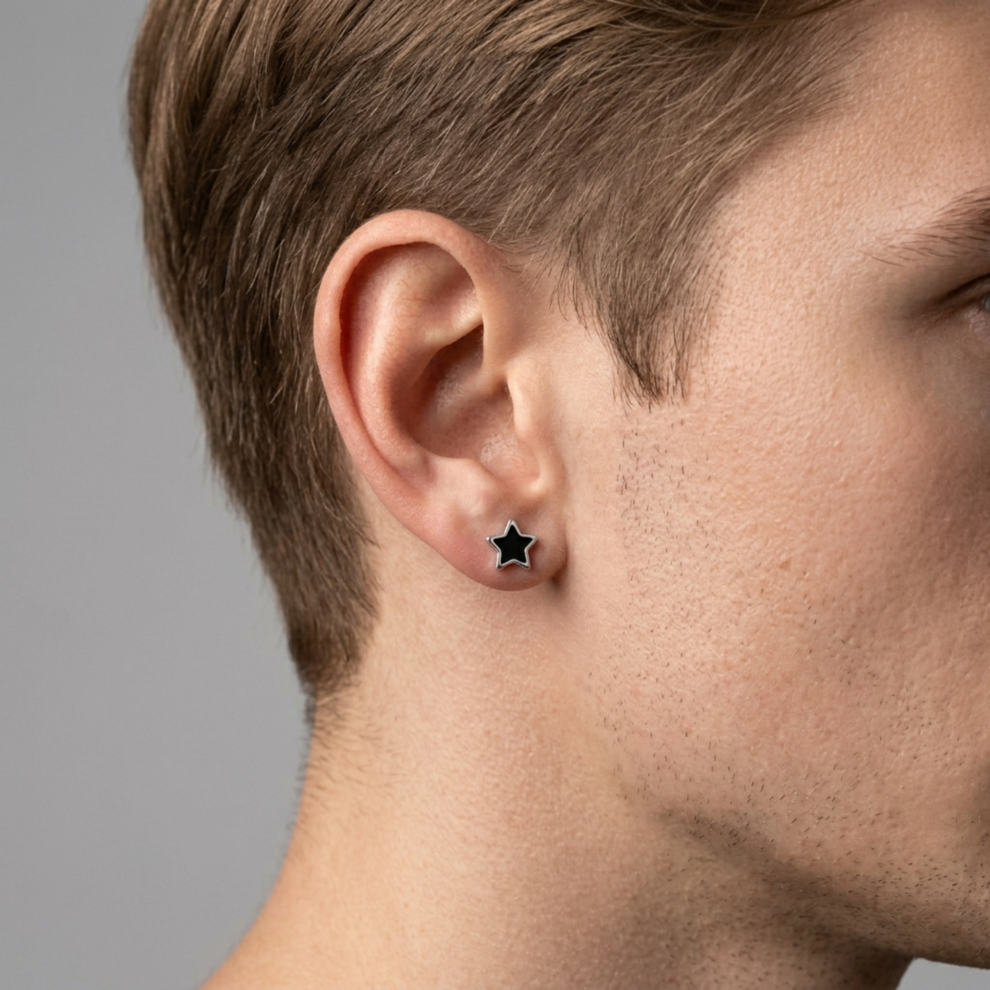 Star stud earrings close-up on ear with black glazed star center and silver-tone border