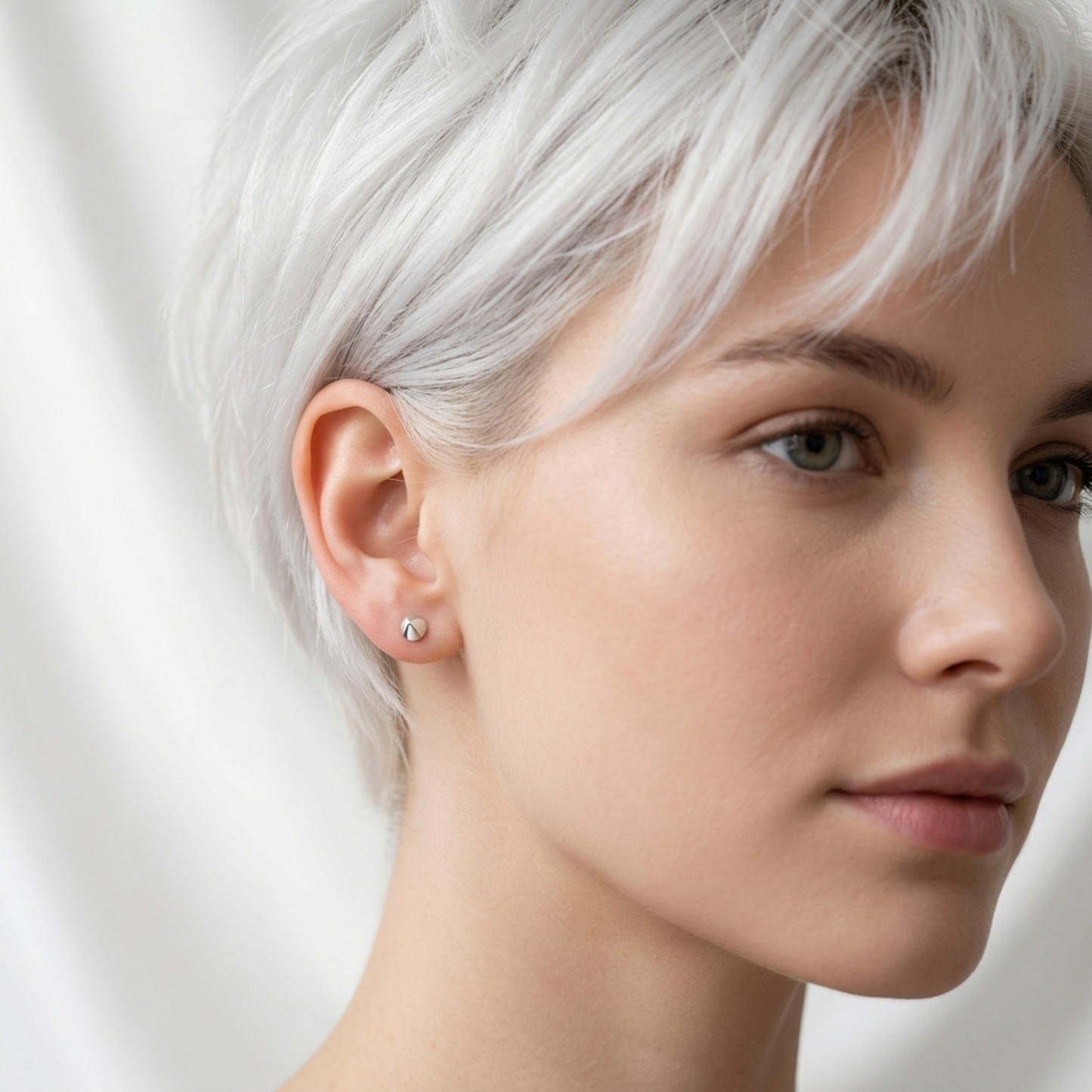 Silver cone spike stud earrings worn by model, small conical spikes on both ears