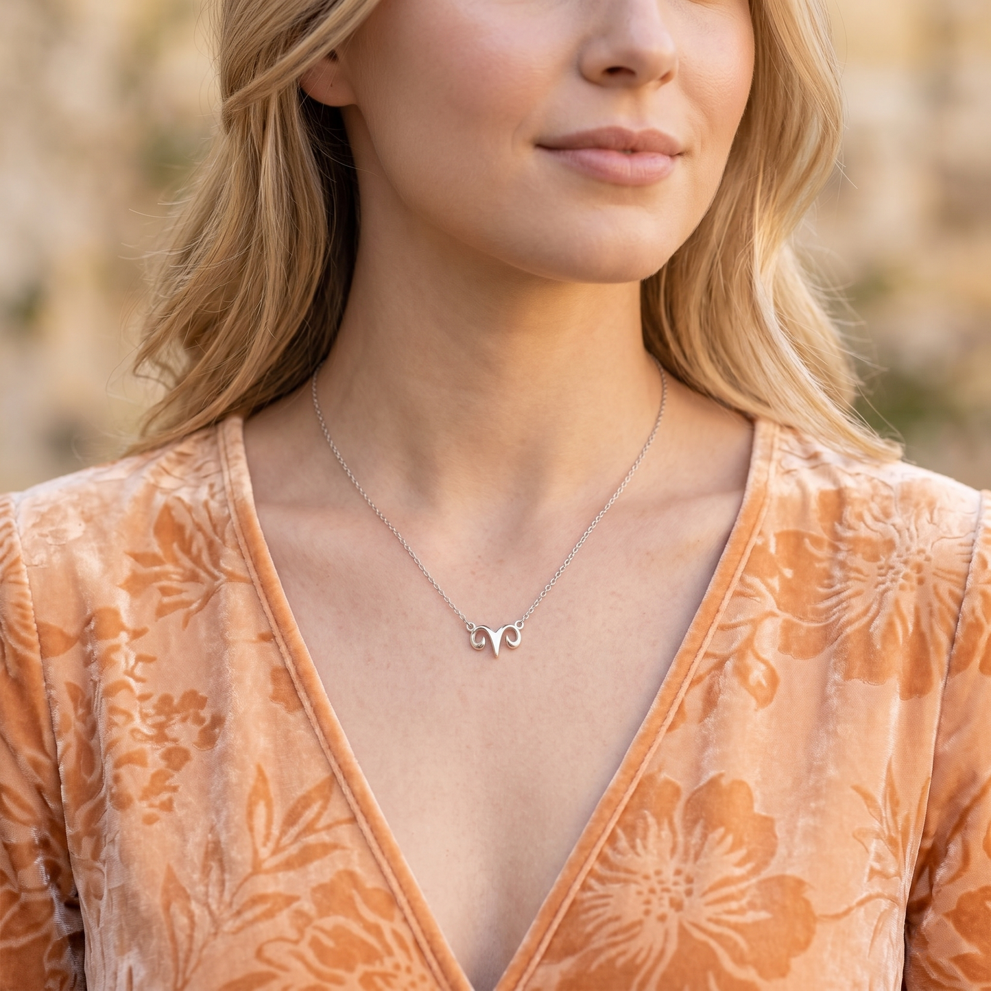 Zodiac pendant necklace worn with ram-horn pendant at chest on silver chain