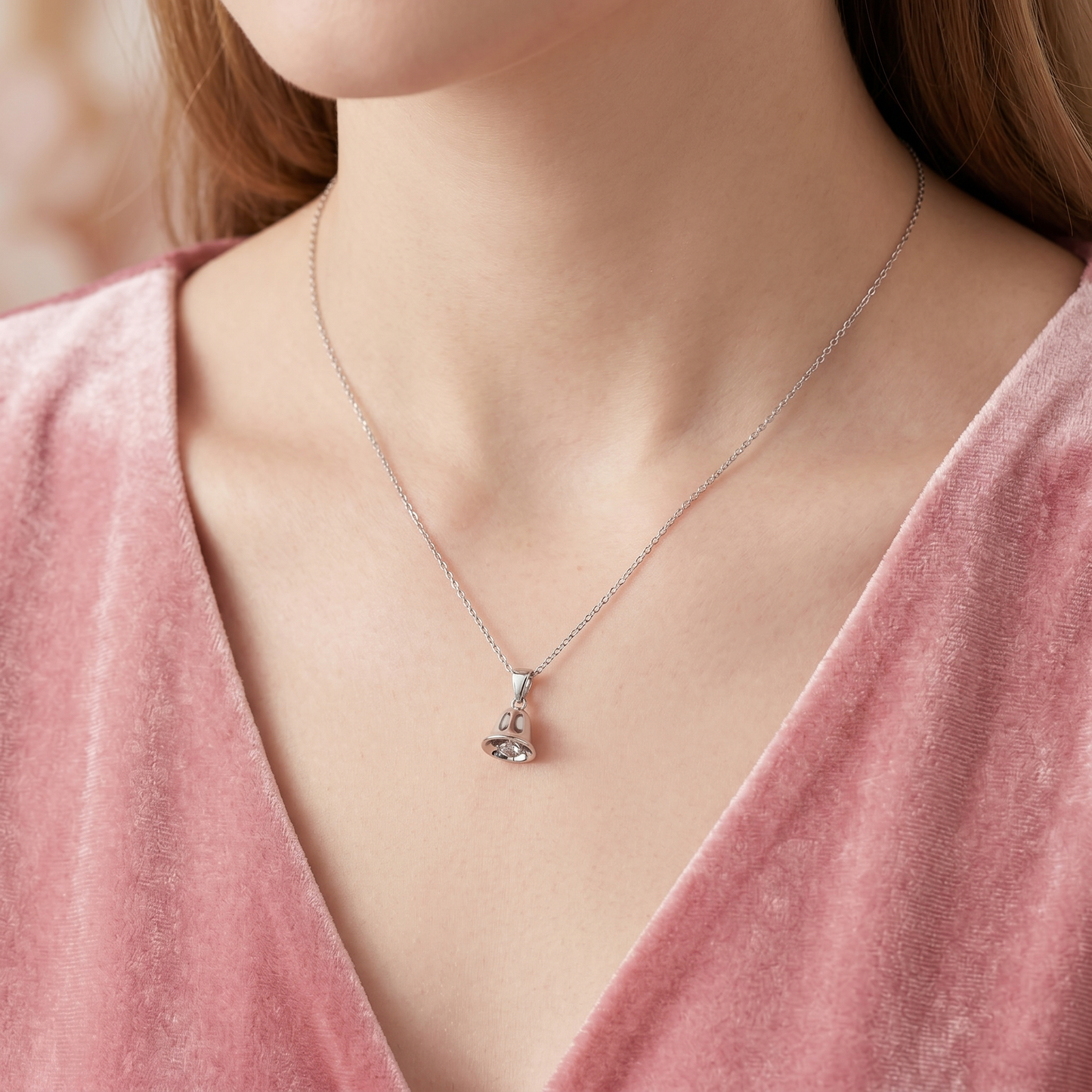 Silver jingle bell necklace with pendant hanging at the collarbone