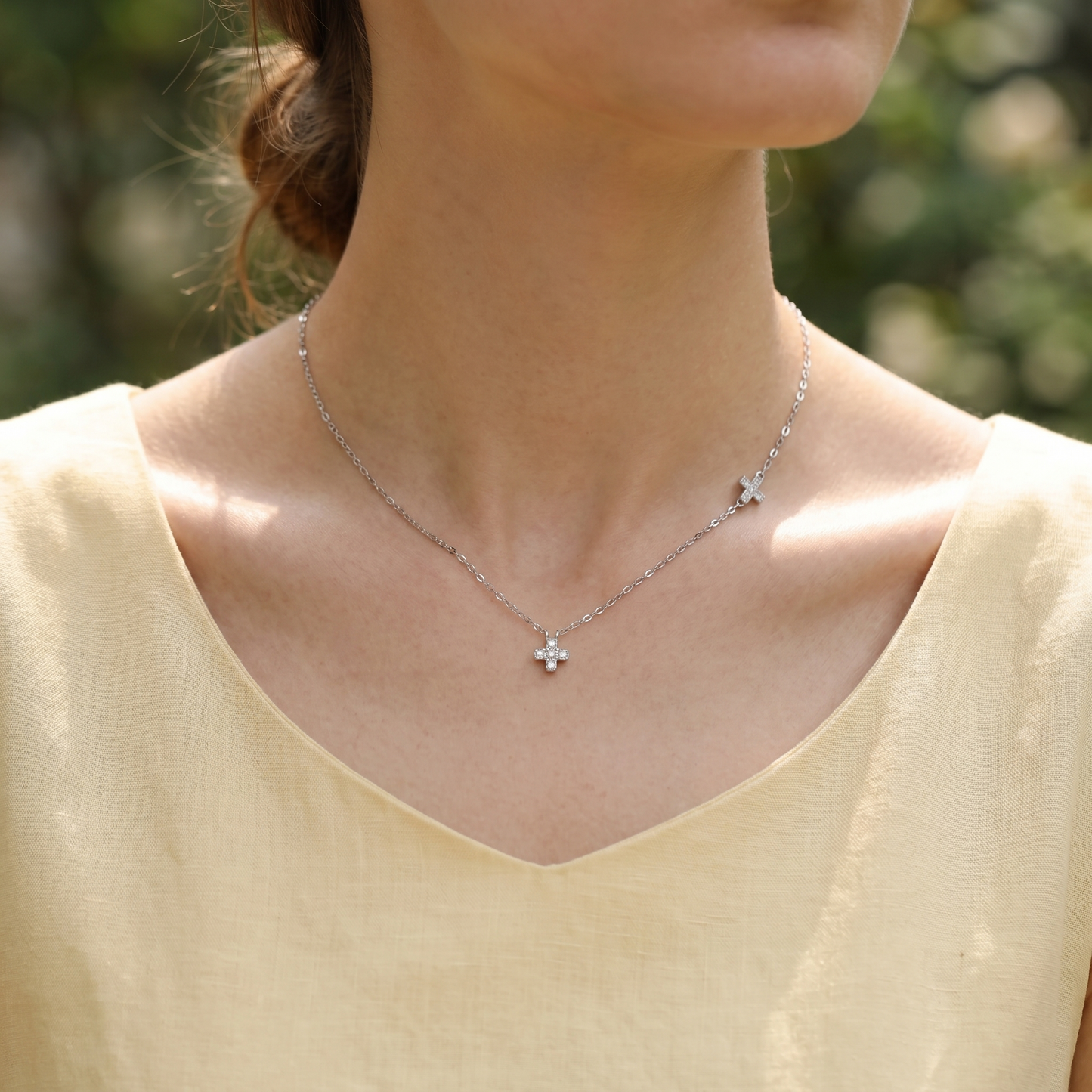 Silver cross necklace with two sideways cross pendants worn at neckline