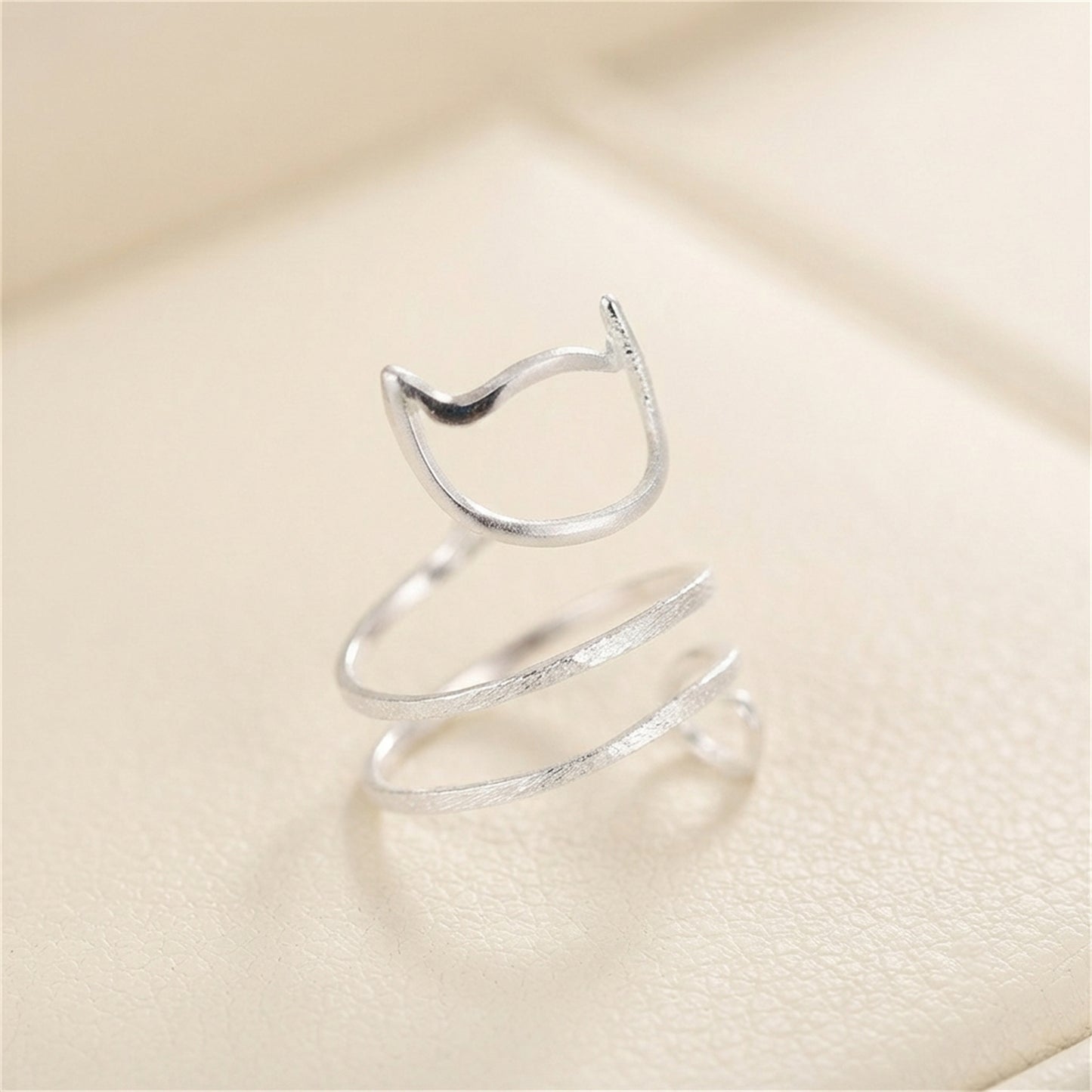 Silver-tone kitten wraparound ring viewed from above, cat-face and spiral tail.