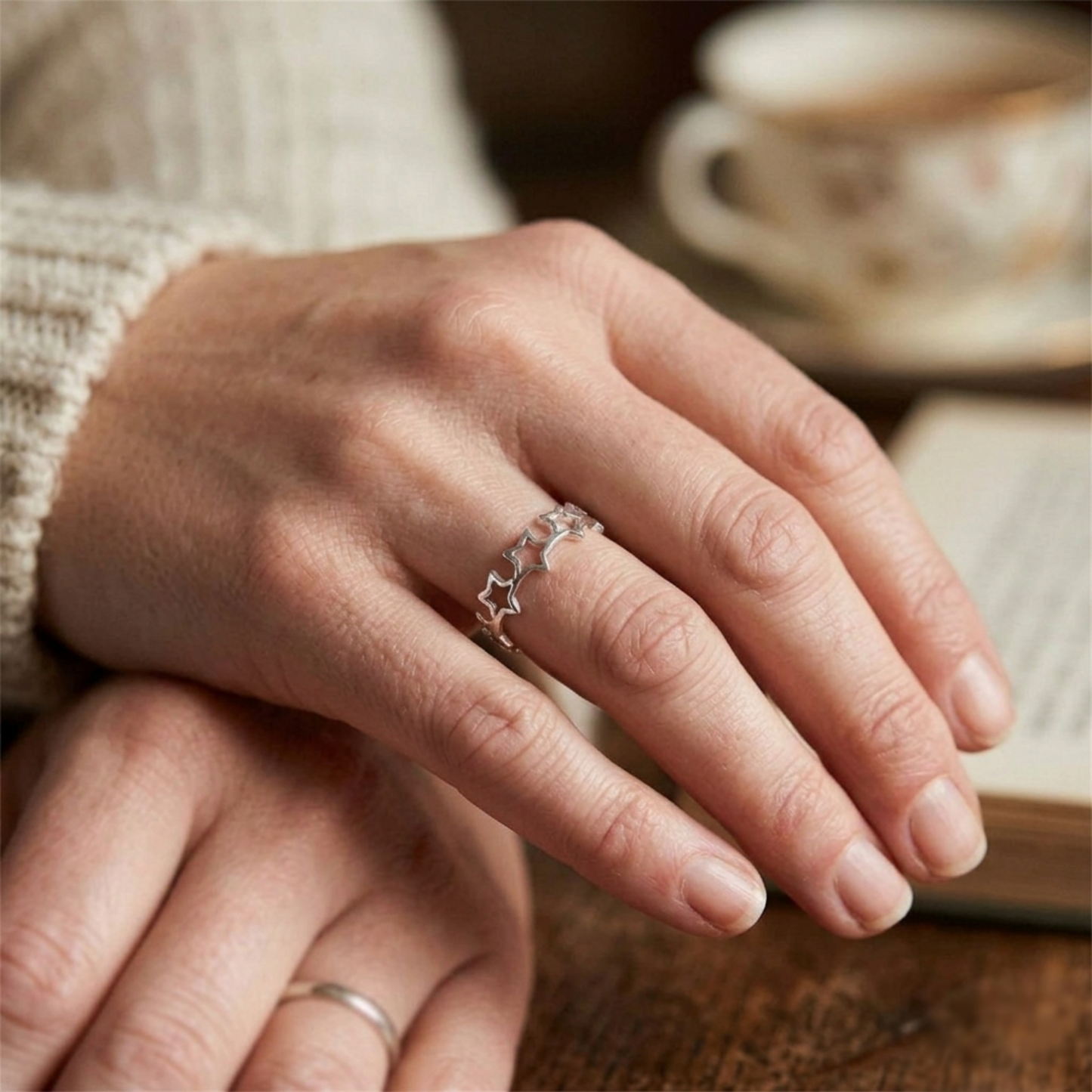 Silver star-linked ring worn on a finger with star motifs on the band