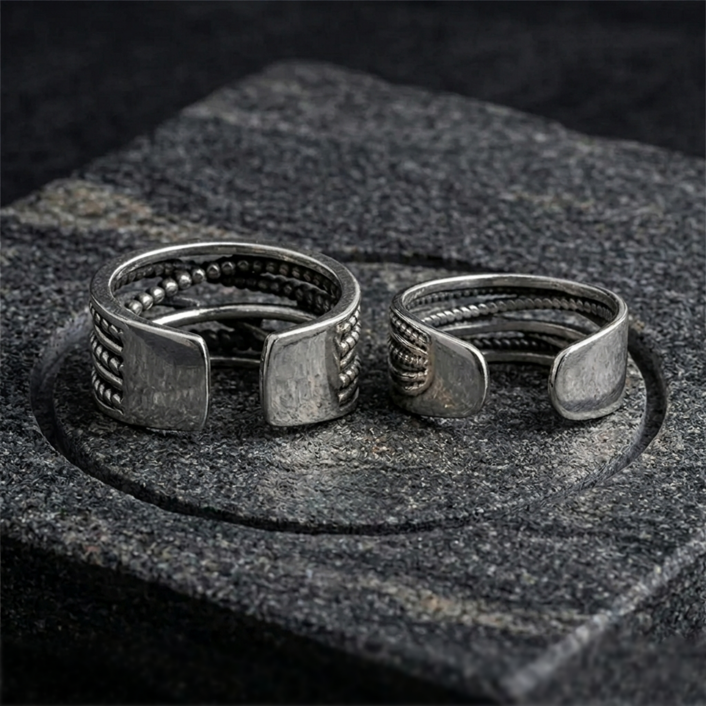 Two oxidised silver-tone rope crossover rings with bead and braided band details.