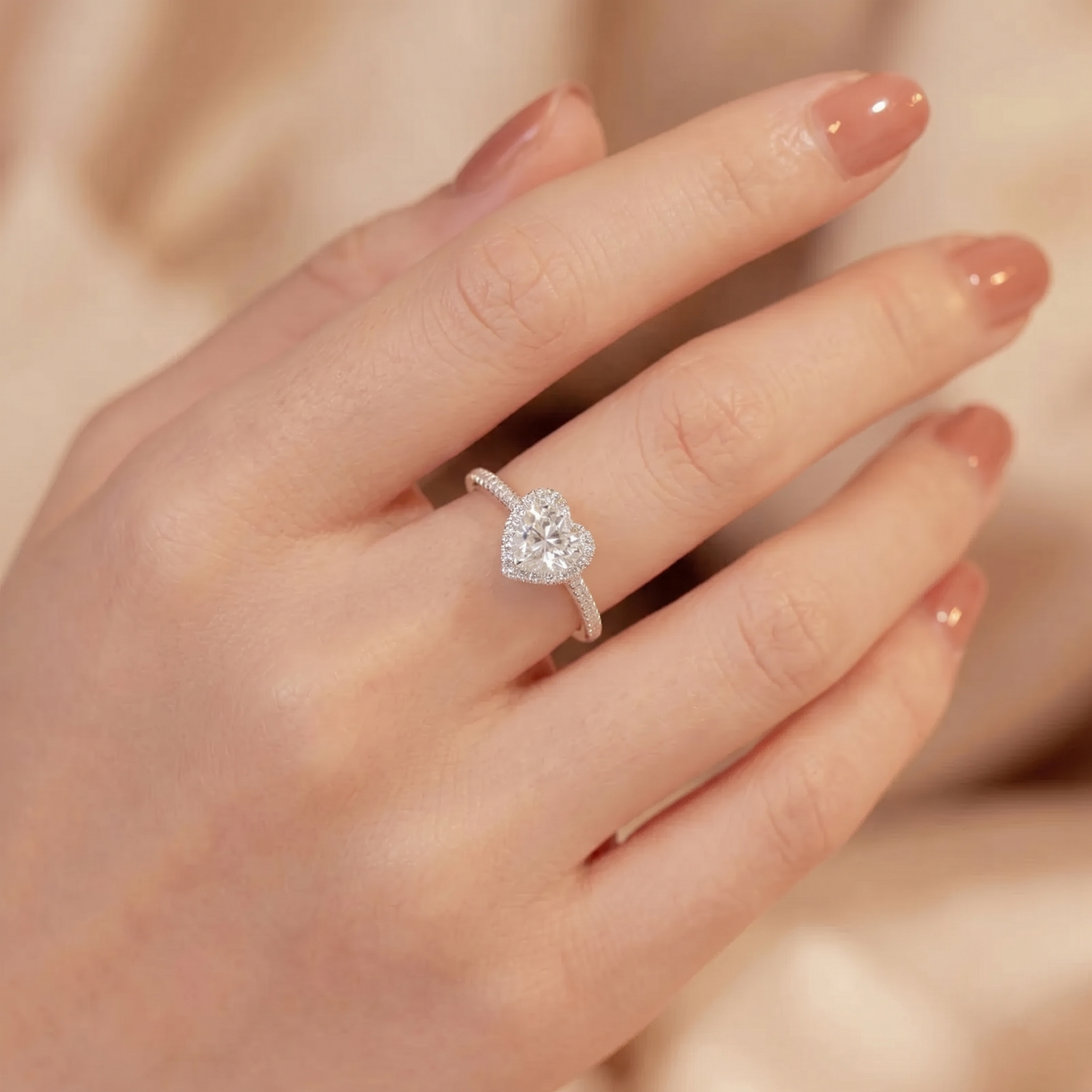 Heart halo ring on hand with heart-shaped center stone and pavé band, side view.