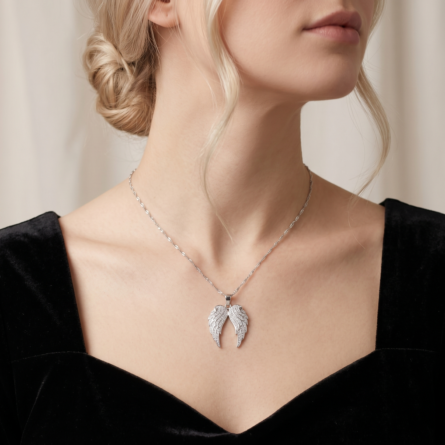 Silver angel wing pendant necklace worn on a delicate chain