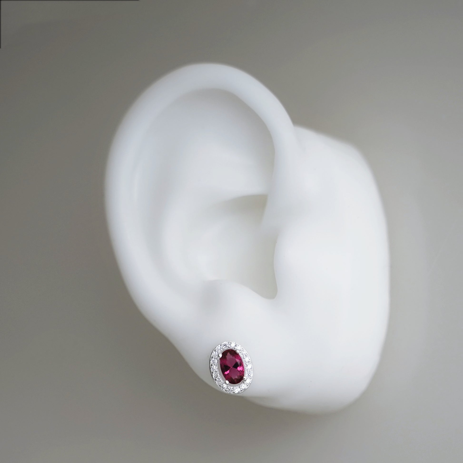 Ruby-red CZ stud earring with oval center stone and silver halo setting