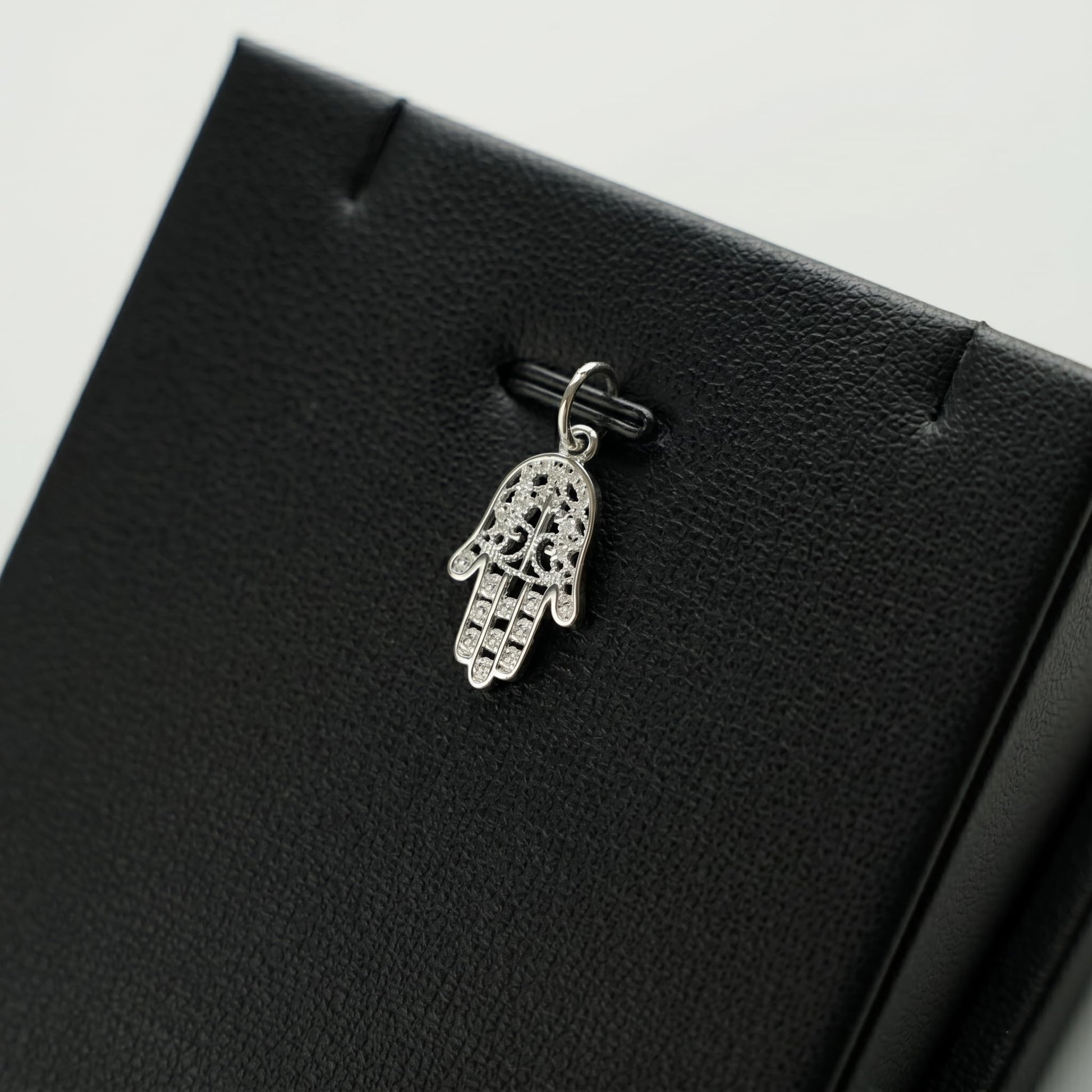 Silver hamsa hand charm pendant with intricate cutout detail and clasp loop