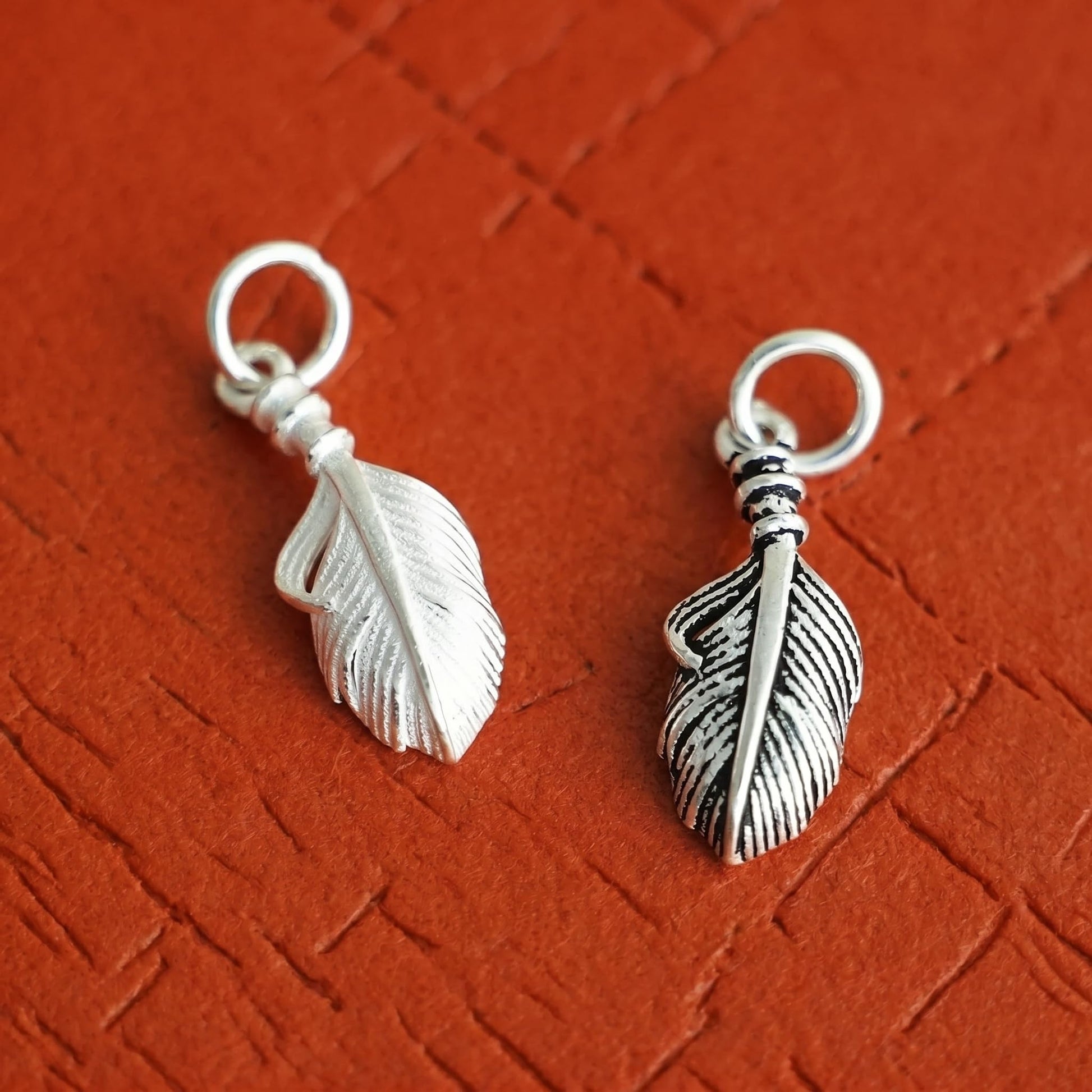 Silver feather wing charm pair, each with loop and detailed feather engraving.