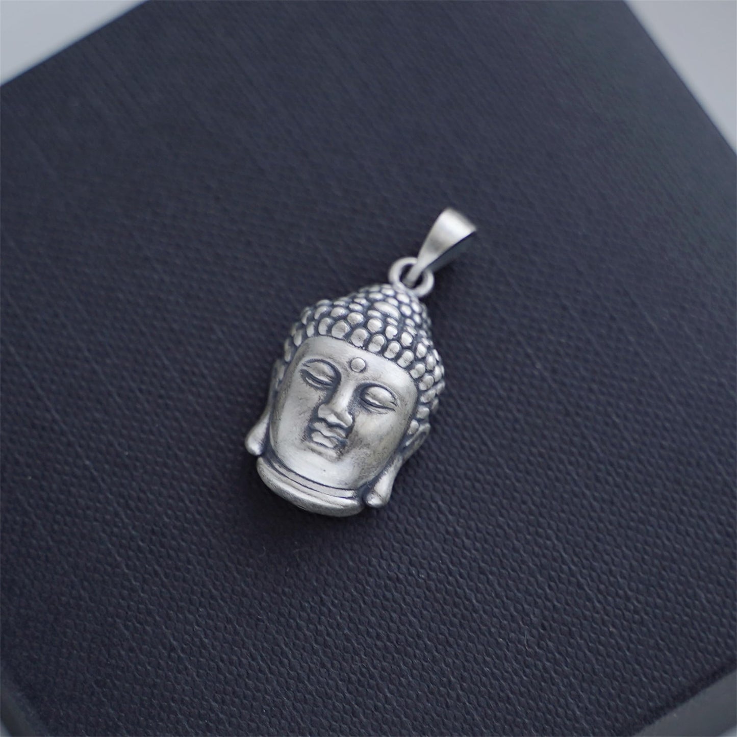 Buddha head pendant, angled view with textured hair, silver-tone