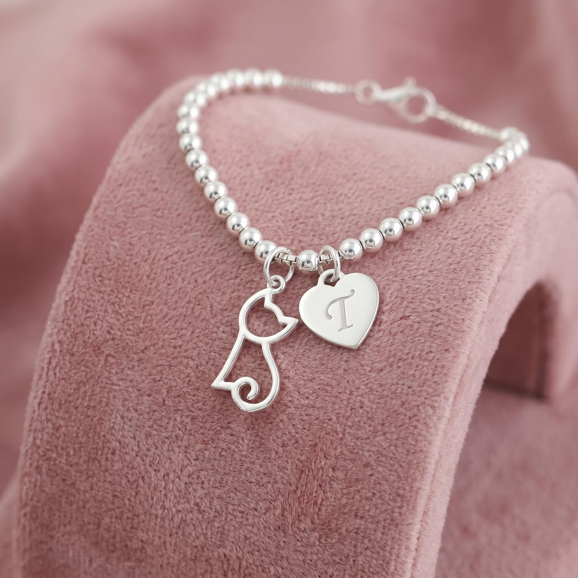 Beaded necklace with silver-tone hollow kitten charm and heart charm, small clasp.
