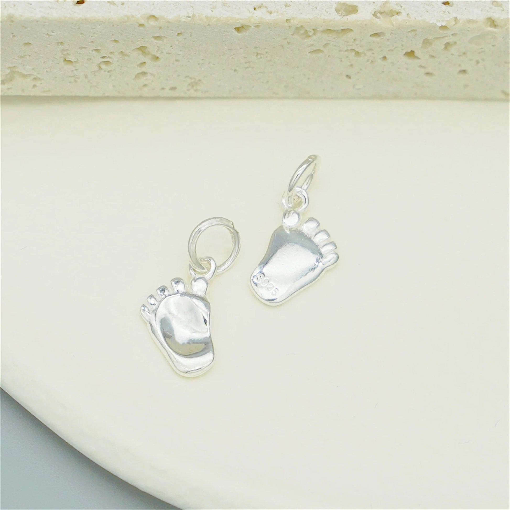 Silver baby foot charm pair with hanging loops and blue enamel sole details