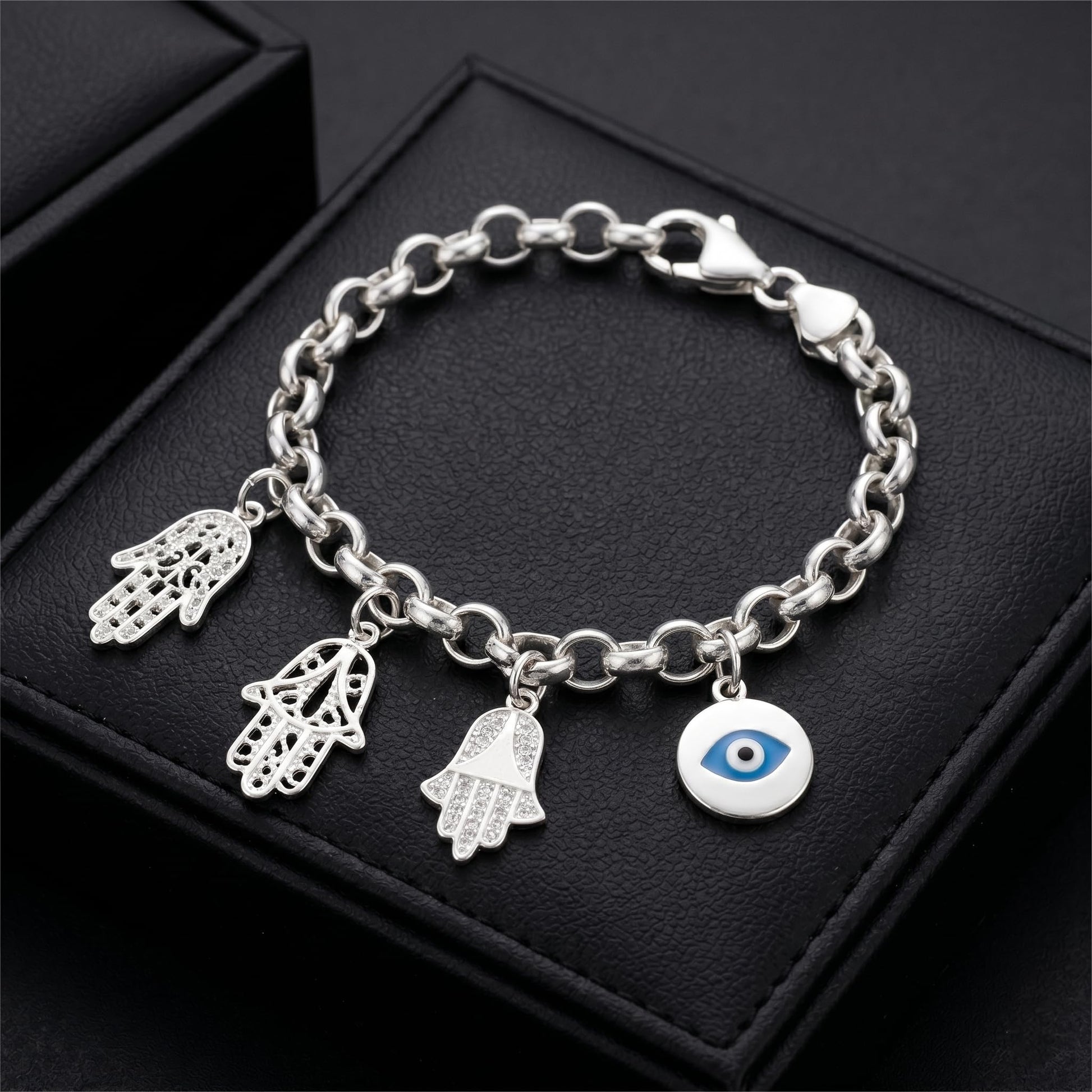 Silver charm bracelet featuring small hamsa hand charms and an blue eye charm