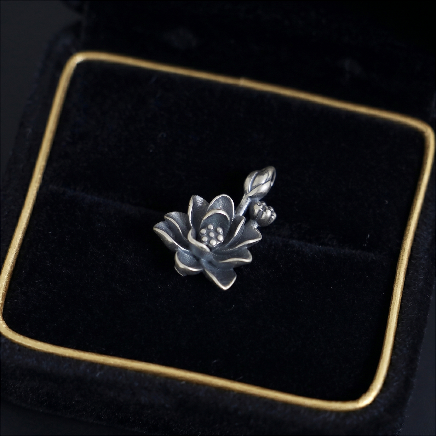 Oxidized lotus flower charm with spiral-style petals and dotted center