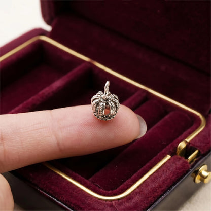Single mini crown charm on fingertip, silver-tone crown with loop bail