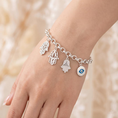 Silver charm bracelet with hamsa hand charms and a blue eye charm on wrist