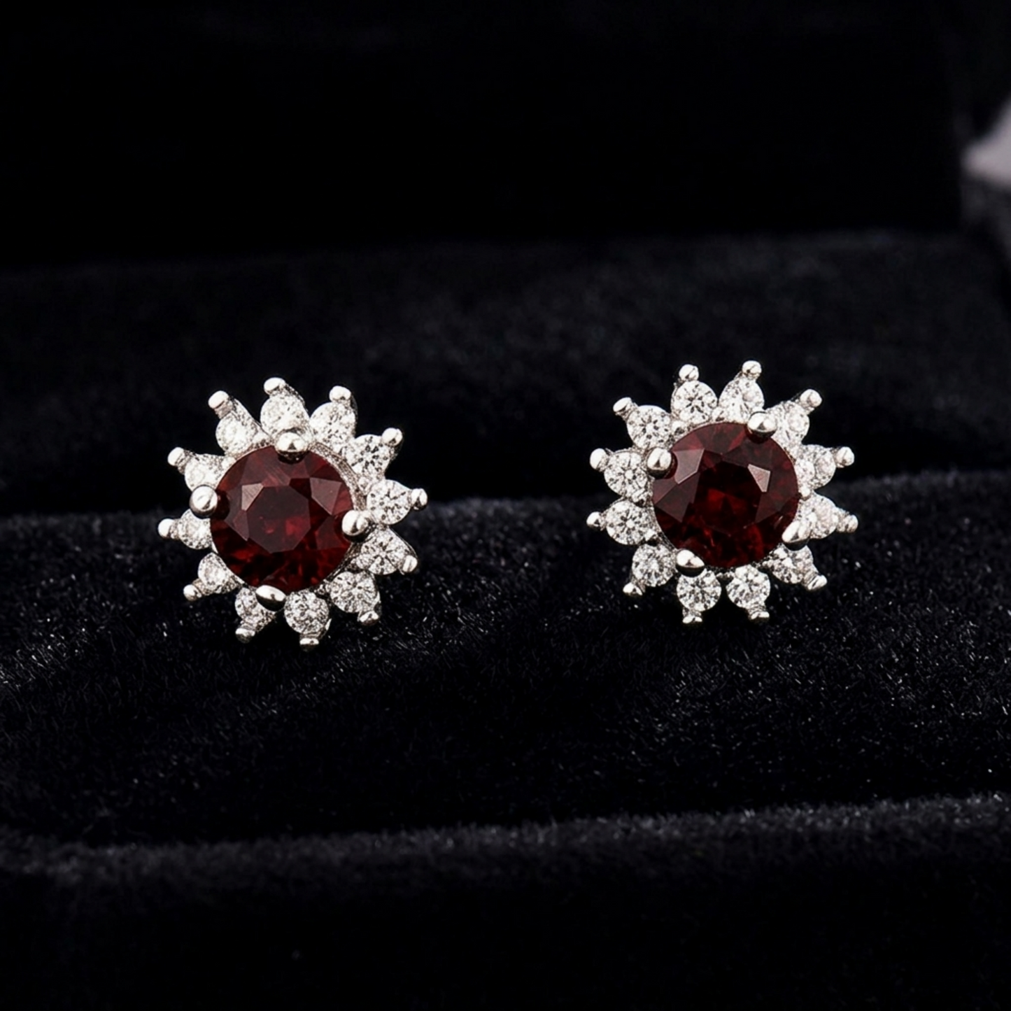 Red oval gemstone cluster earrings on dark velvet