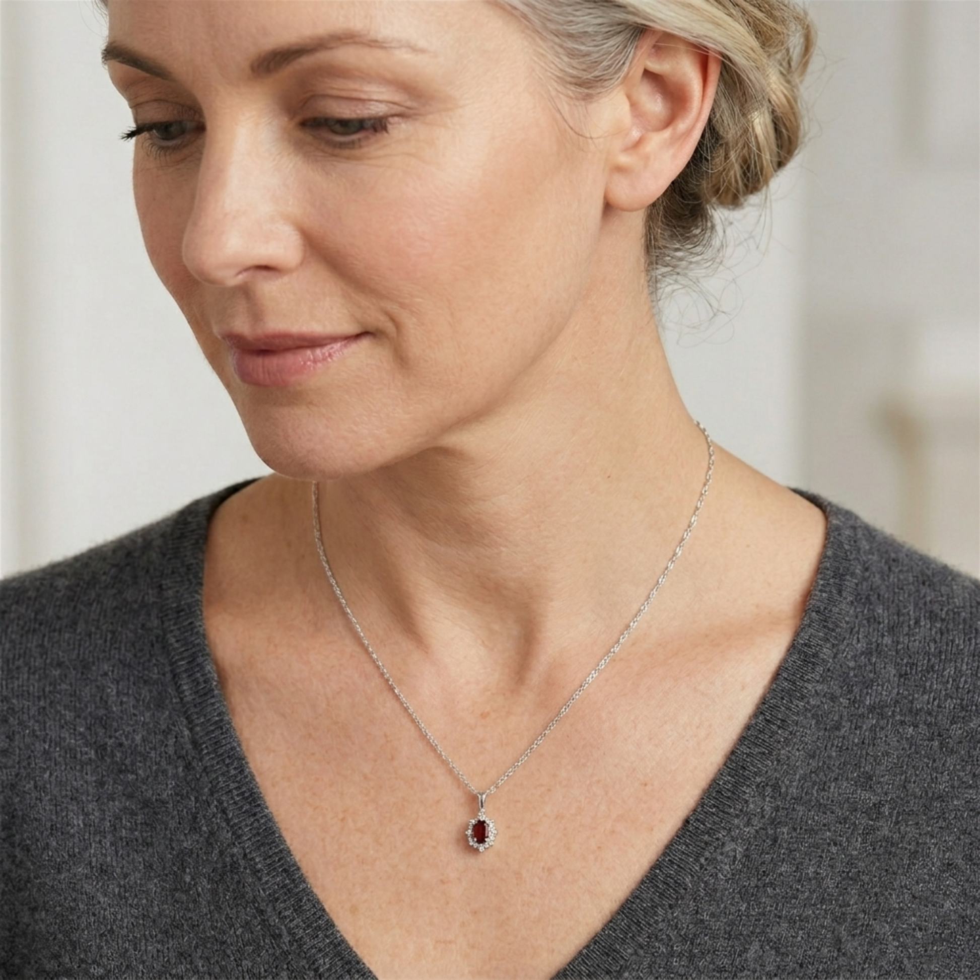 Silver-tone necklace with dark red oval gemstone cluster pendant on a thin chain.