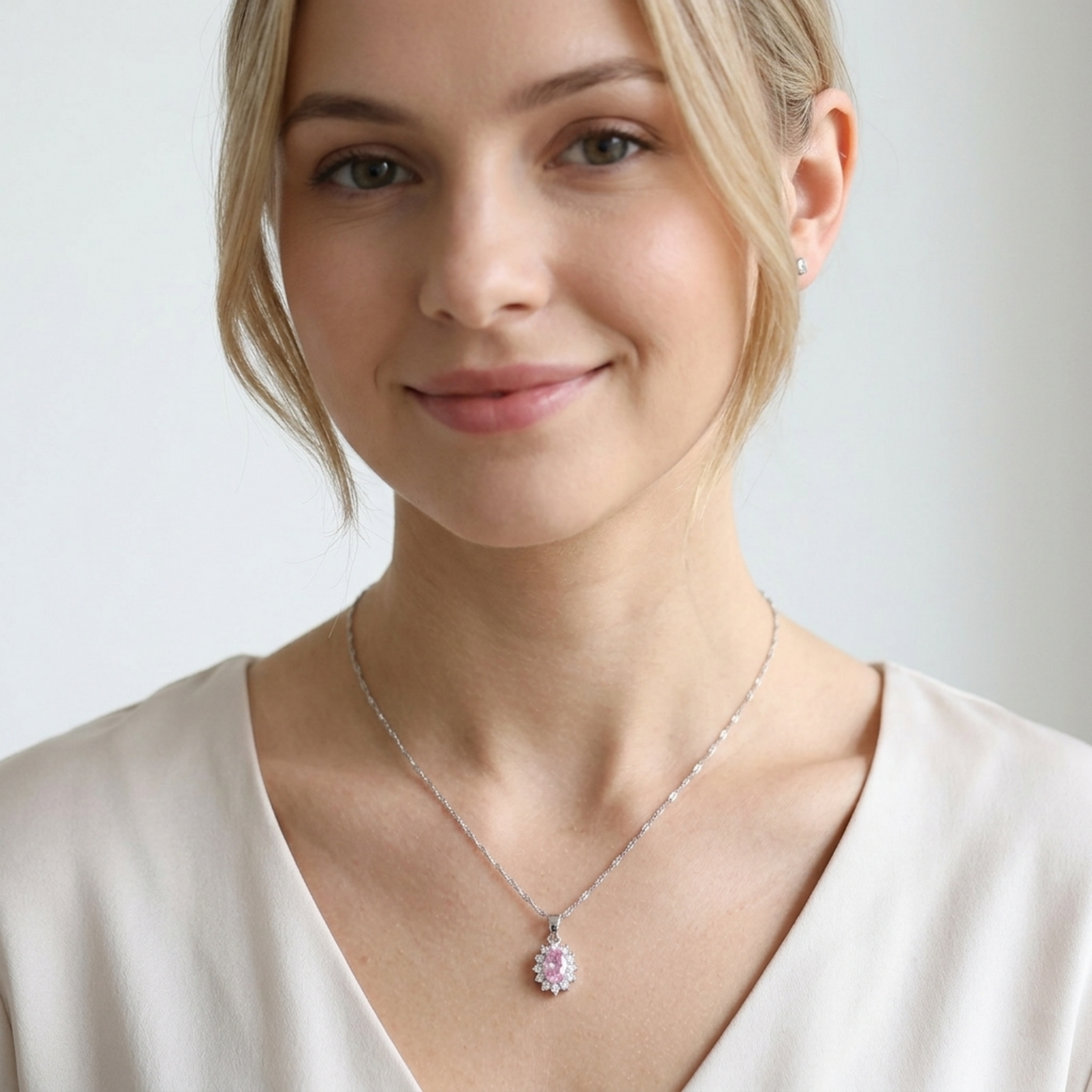 Silver-tone necklace with oval pink gemstone cluster pendant on a thin chain.