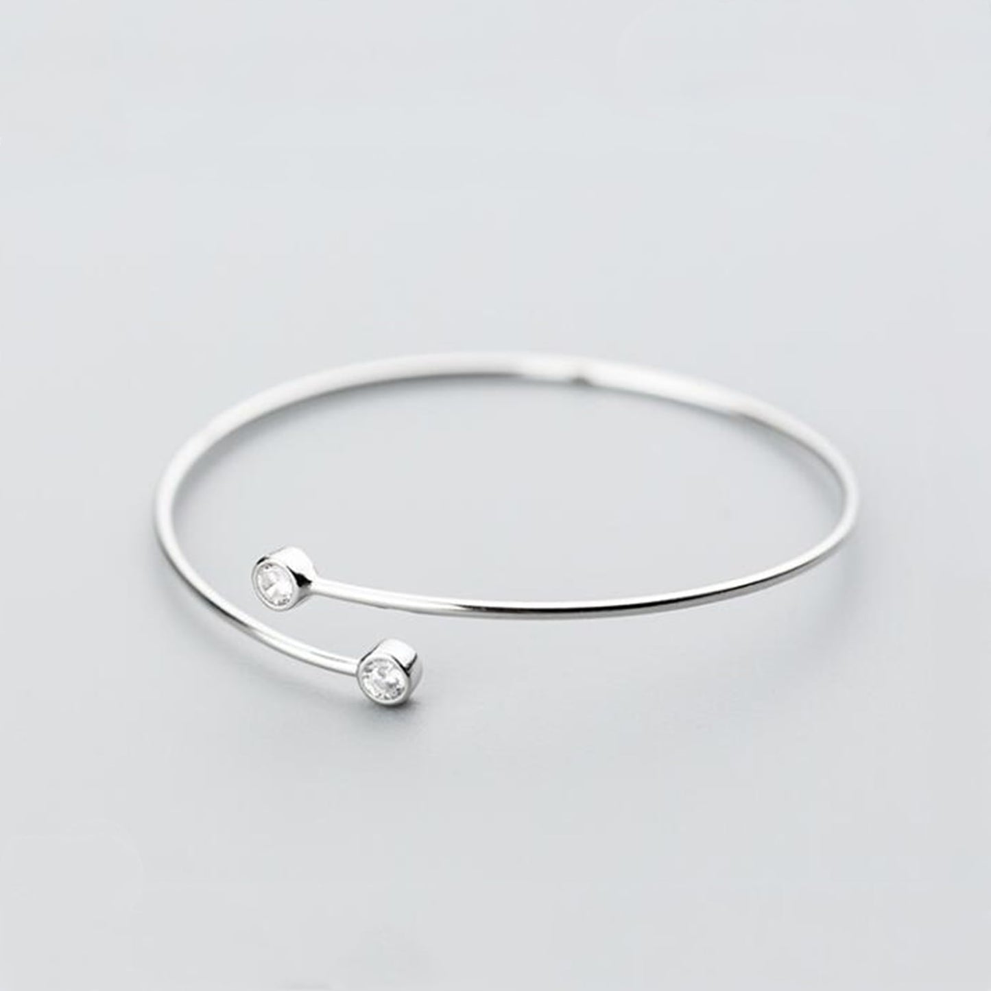 Silver-tone torque bangle with two round CZ stones and slim open cuff