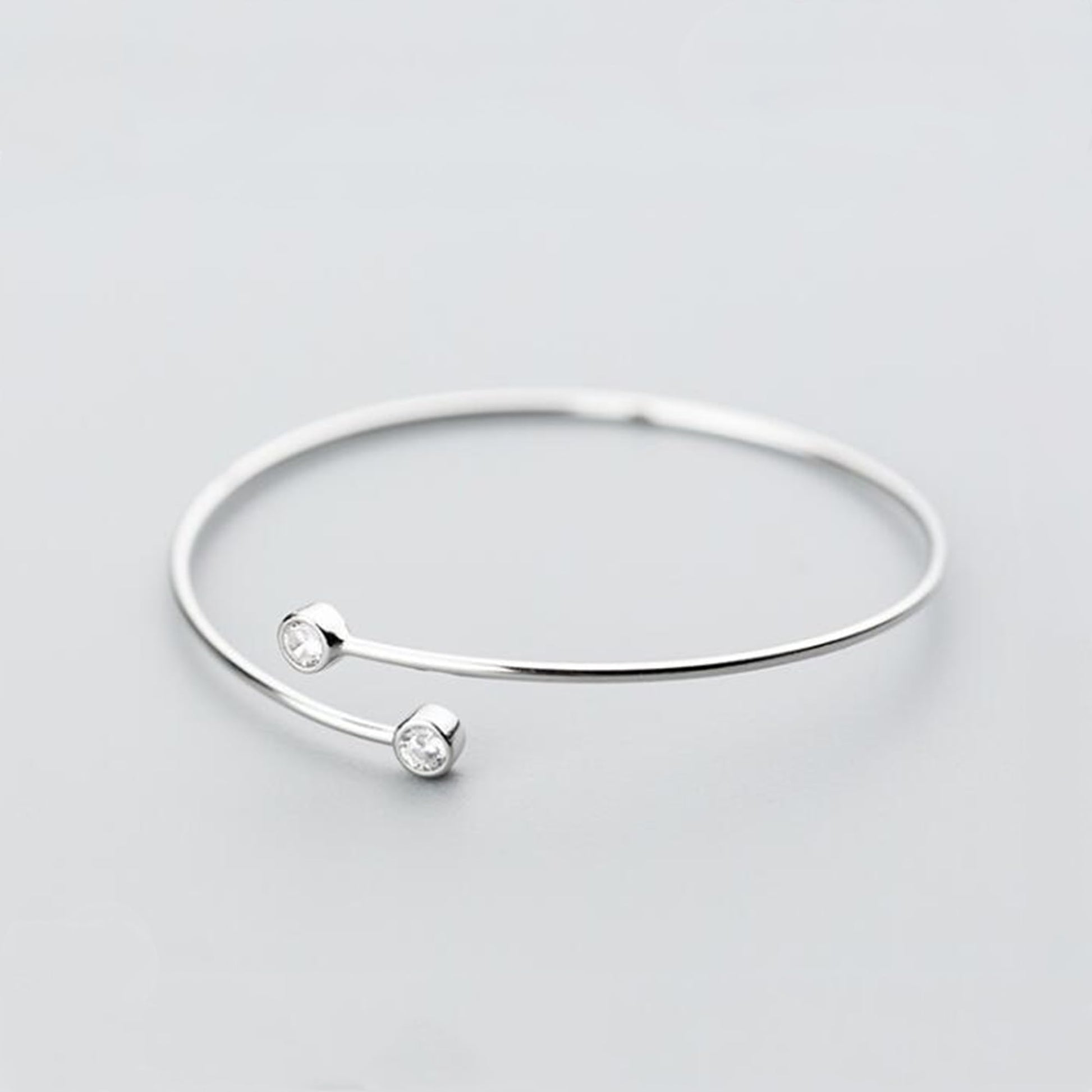 Silver-tone torque bangle with two round CZ stones and slim open cuff
