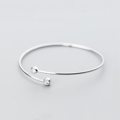 Silver-tone torque bangle with two round CZ stones and slim open cuff