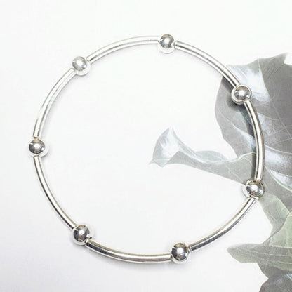 Silver bead stretch bracelet featuring spherical bead ends