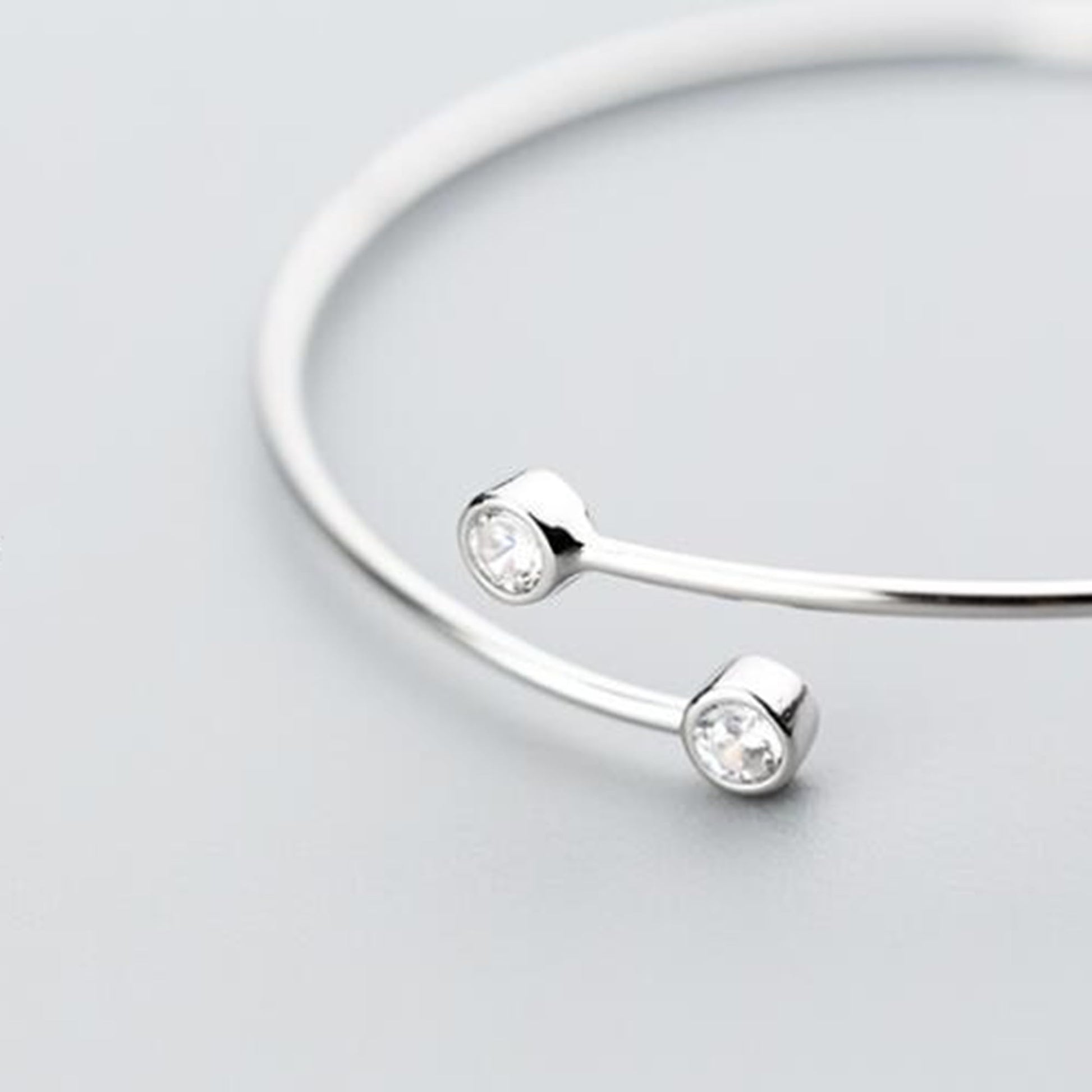 Silver-tone torque bangle with two round CZ stones on curved front bar