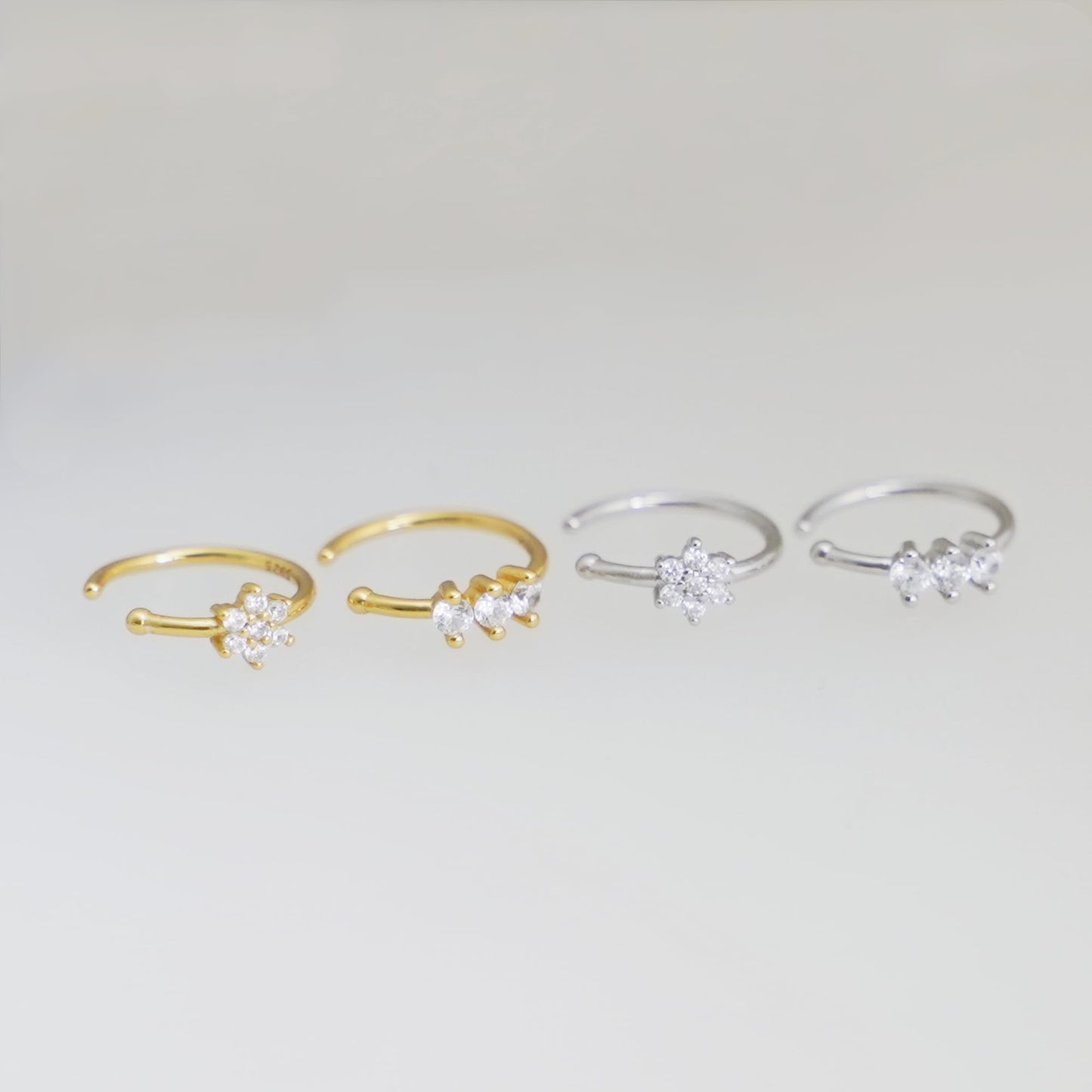 Four CZ cuff hoop rings with floral clusters in gold and silver finishes.