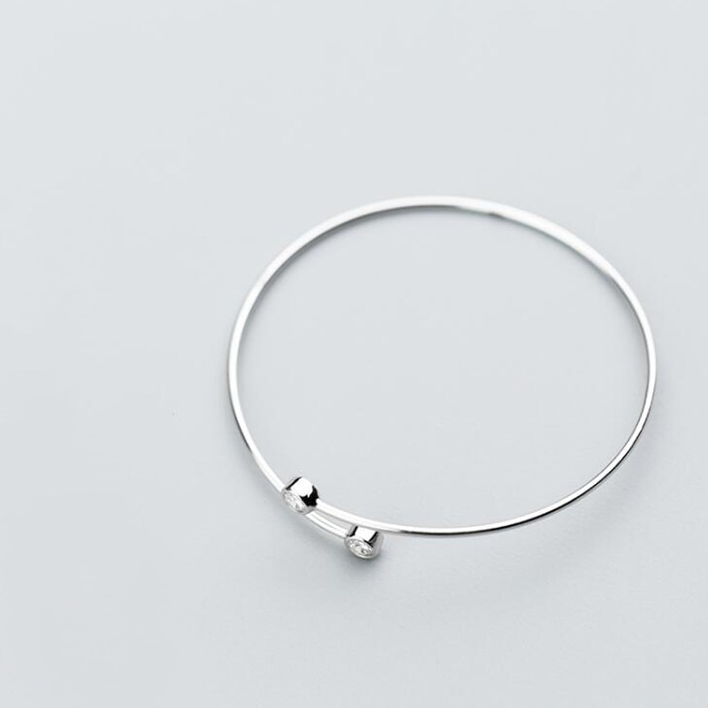 Silver-tone open torque bangle with two round CZ stones at opposite ends
