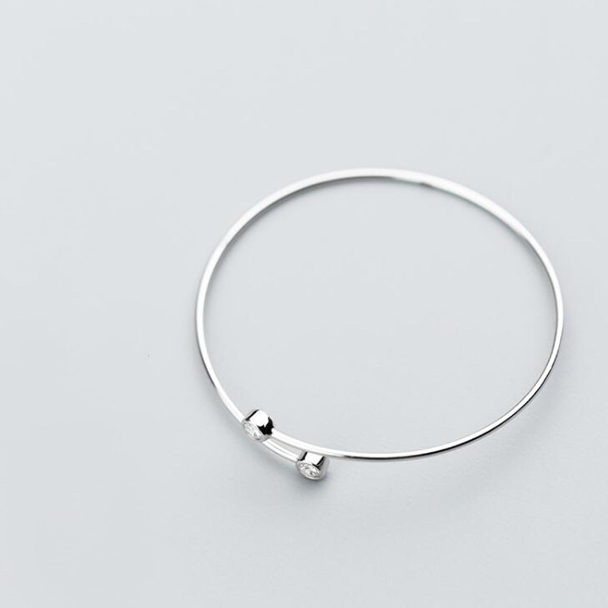 Silver-tone open torque bangle with two round CZ stones at opposite ends