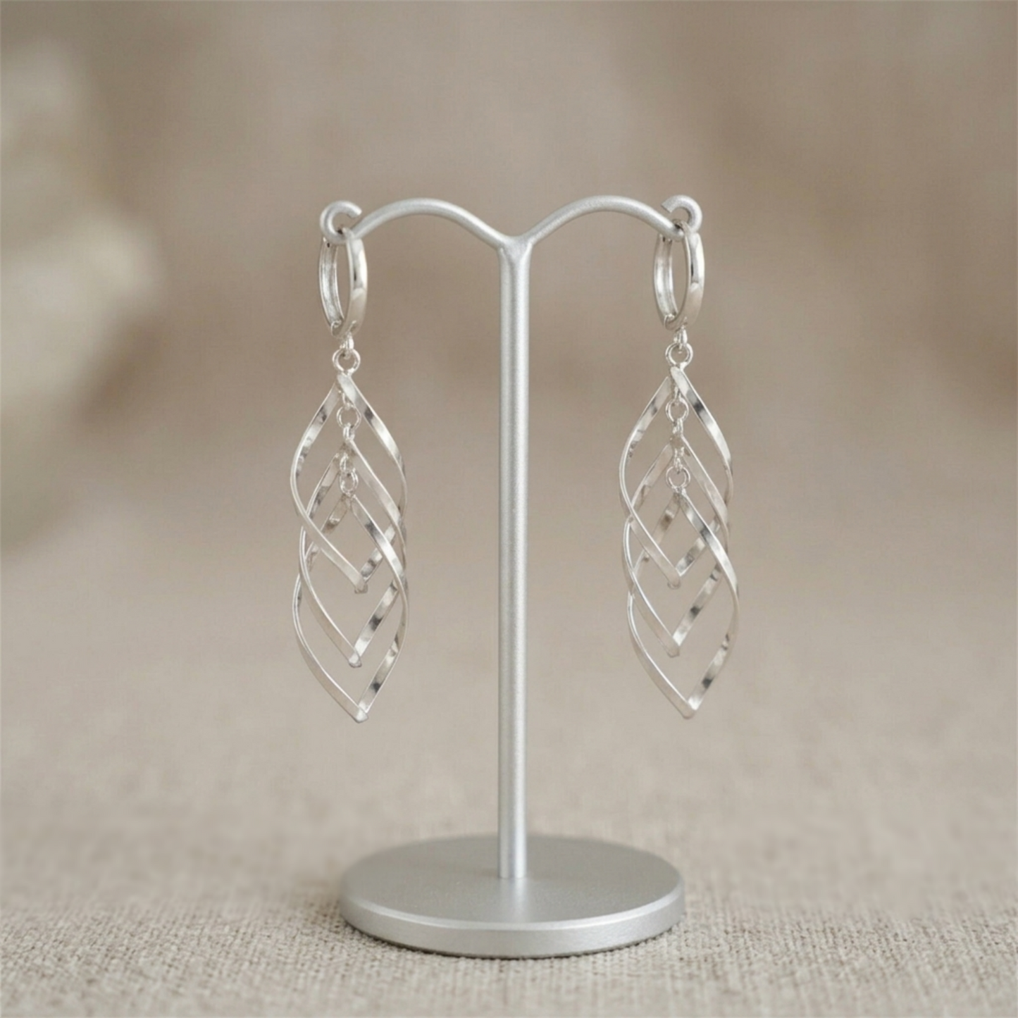 Silver-tone long hanging hoop earrings with overlapping lattice design, on stand