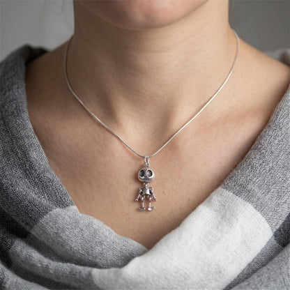 Ghost face pendant worn on a thin silver chain necklace over a gray shirt