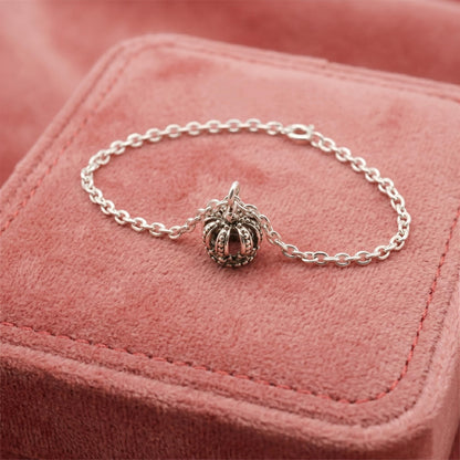 Crown charm bracelet resting on fabric, silver-tone chain with mini crown centerpiece