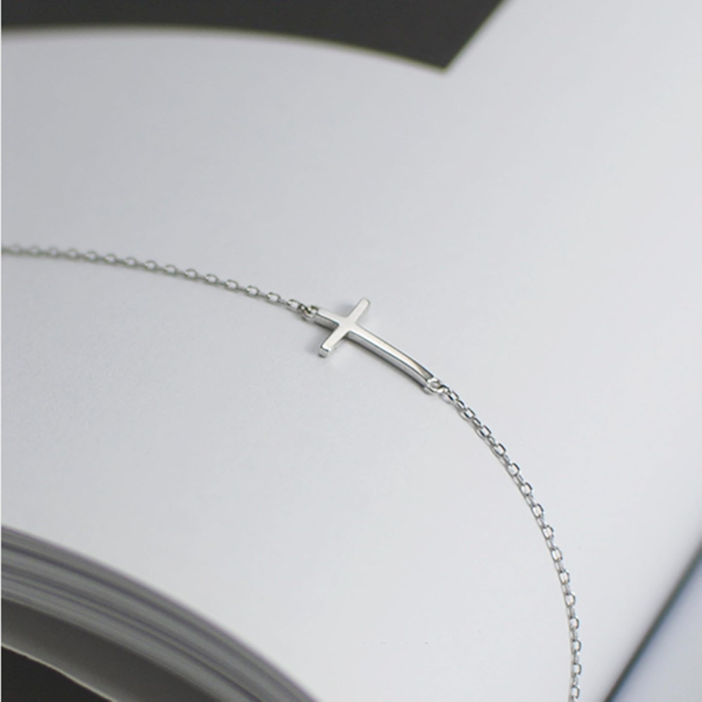 Silver-tone cross anklet bracelet with sideways cross charm, partial view.