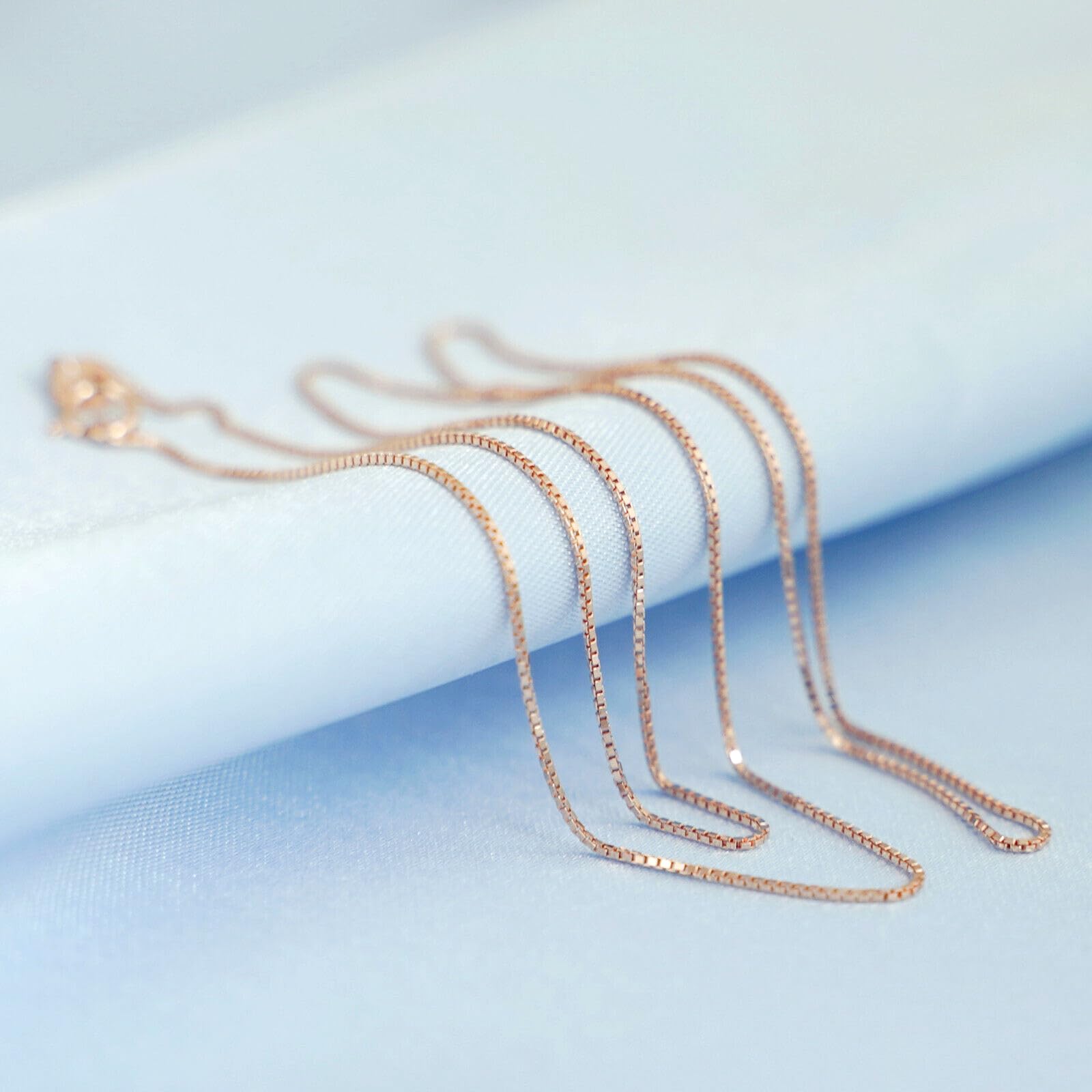 Rose gold-tone box chain necklace strand with small clasp, close-up