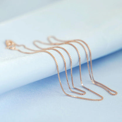 Rose gold-tone box chain necklace strand with small clasp, close-up