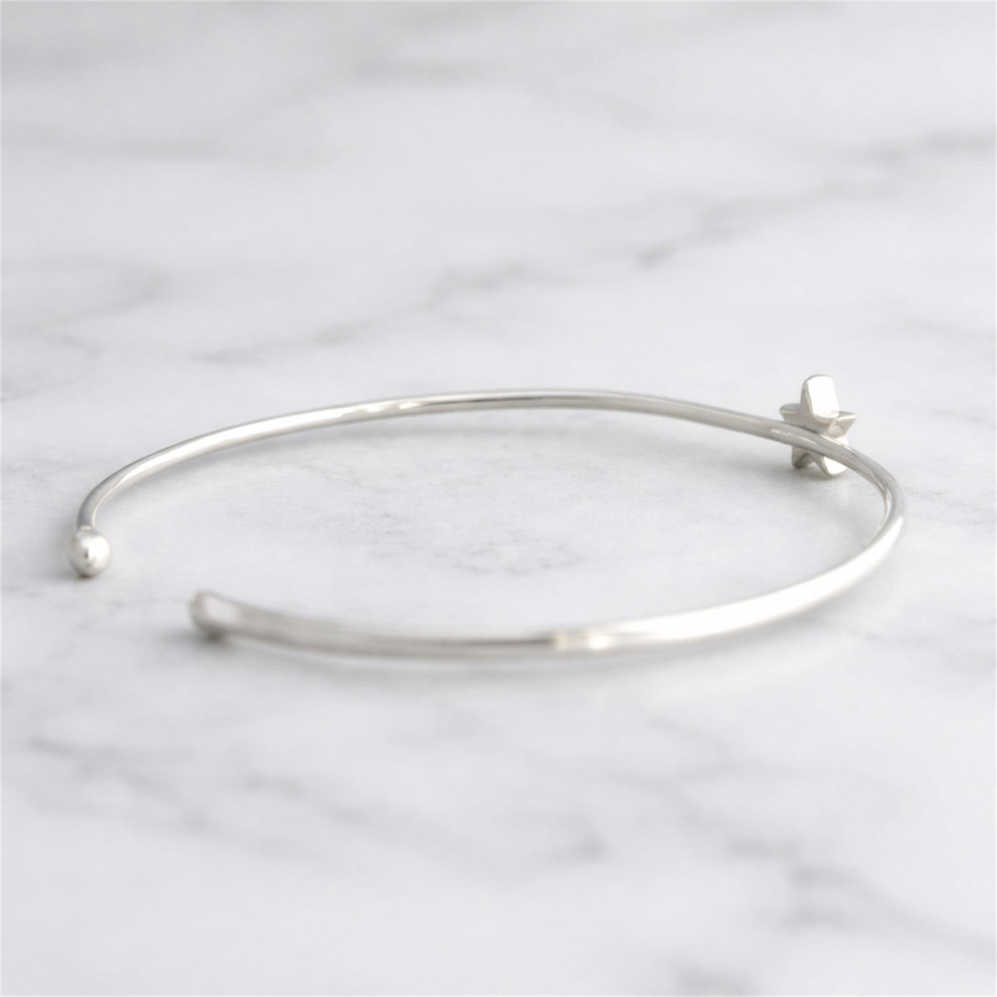 Silver star charm torque bangle bracelet with star detail near clasp