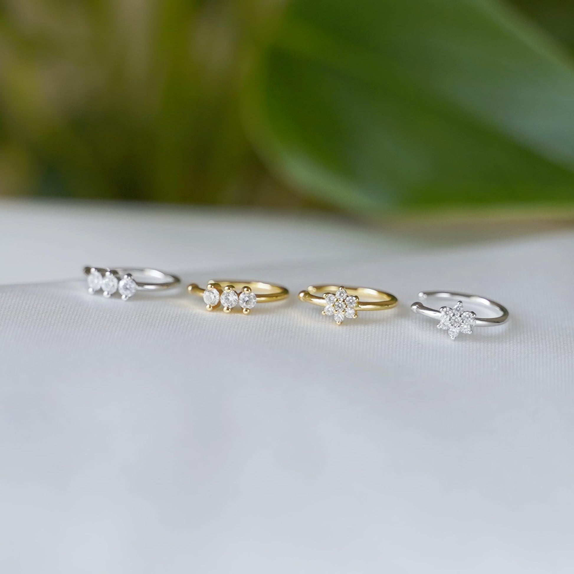 Three CZ floral cuff hoops with small flower clusters on display, mixed silver and gold.