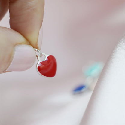 Red heart charm with silver loop, held by hand