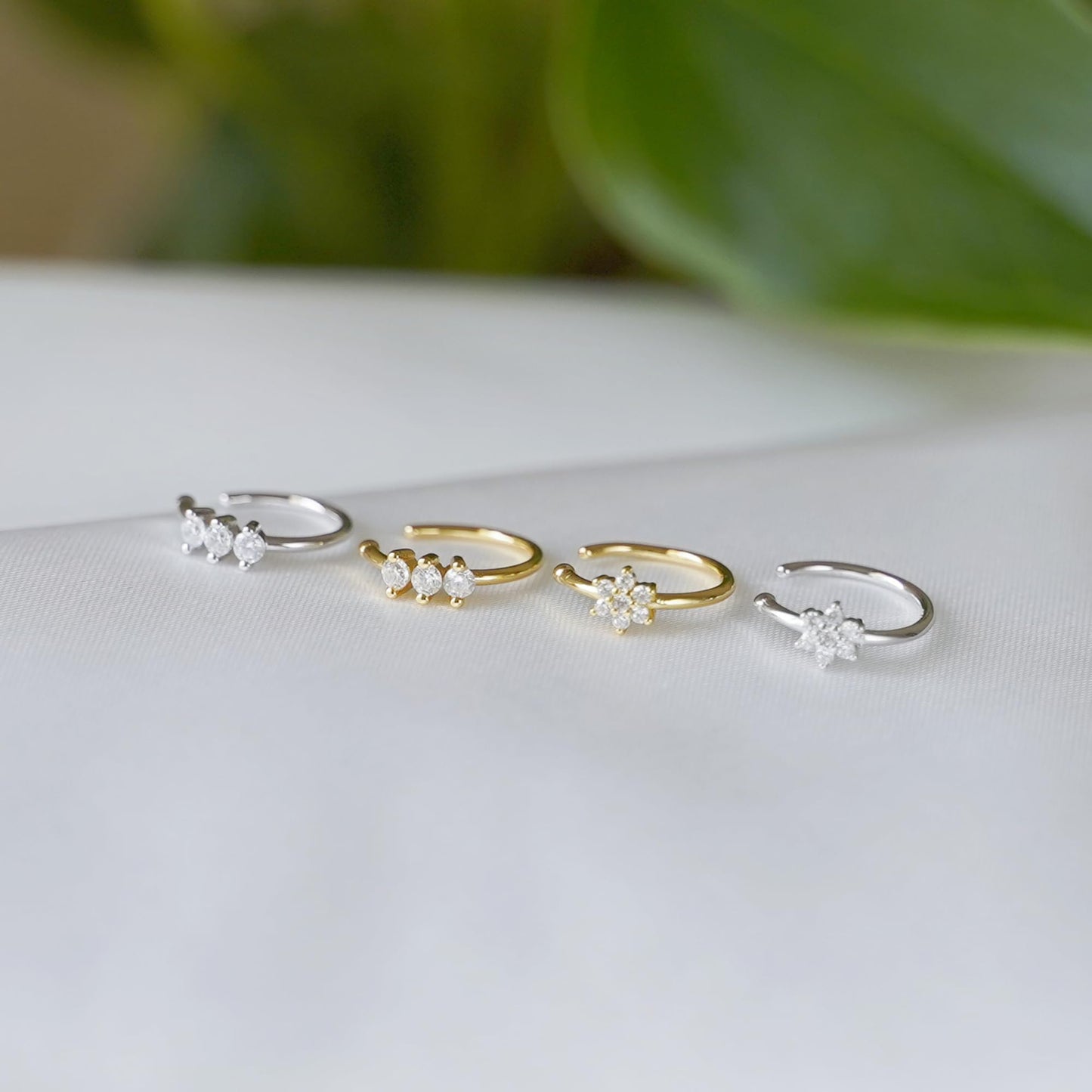 Four CZ floral cuff hoops with small flower clusters on display, silver and gold.
