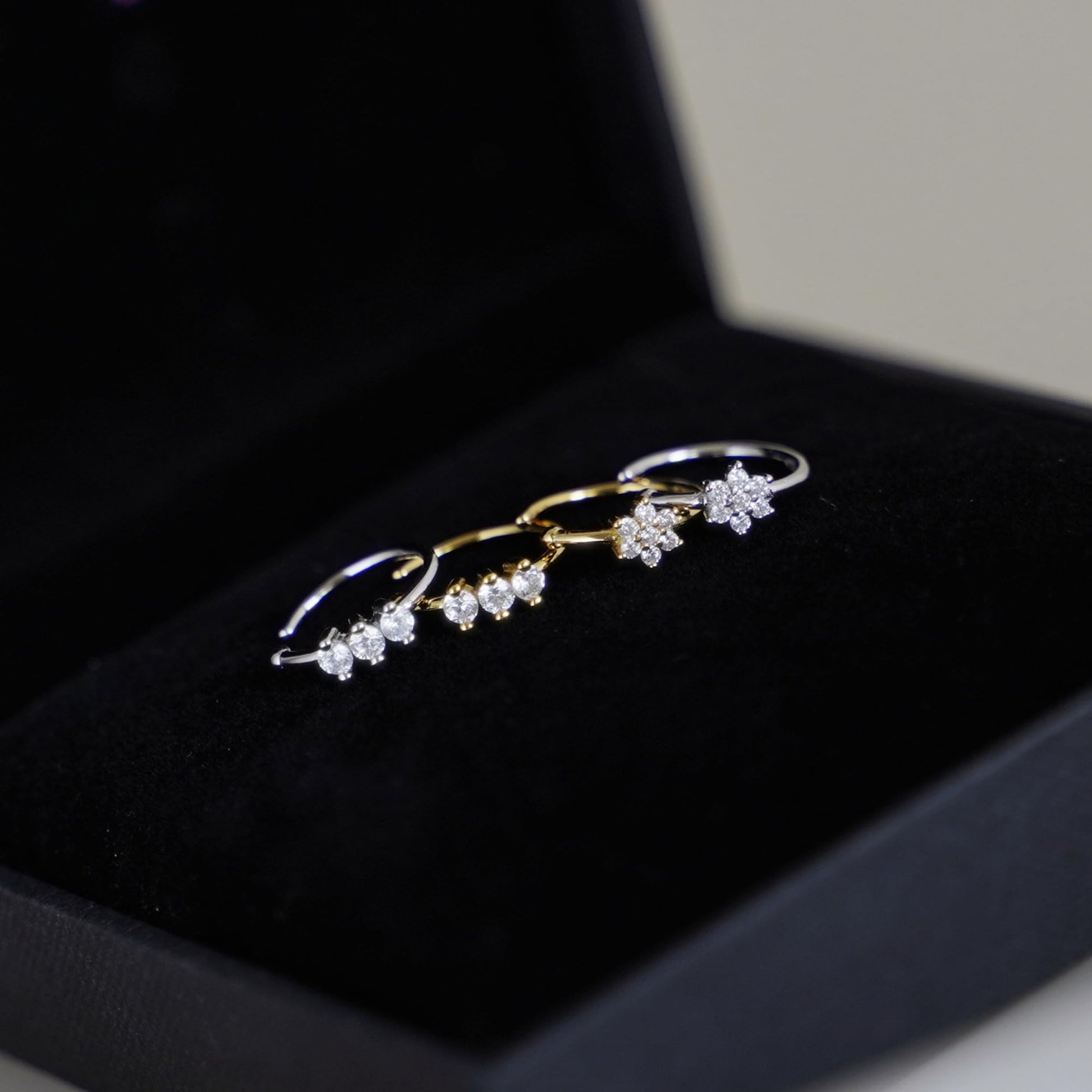 CZ floral cuff hoops in a jewelry box: one gold-tone and one silver-tone.
