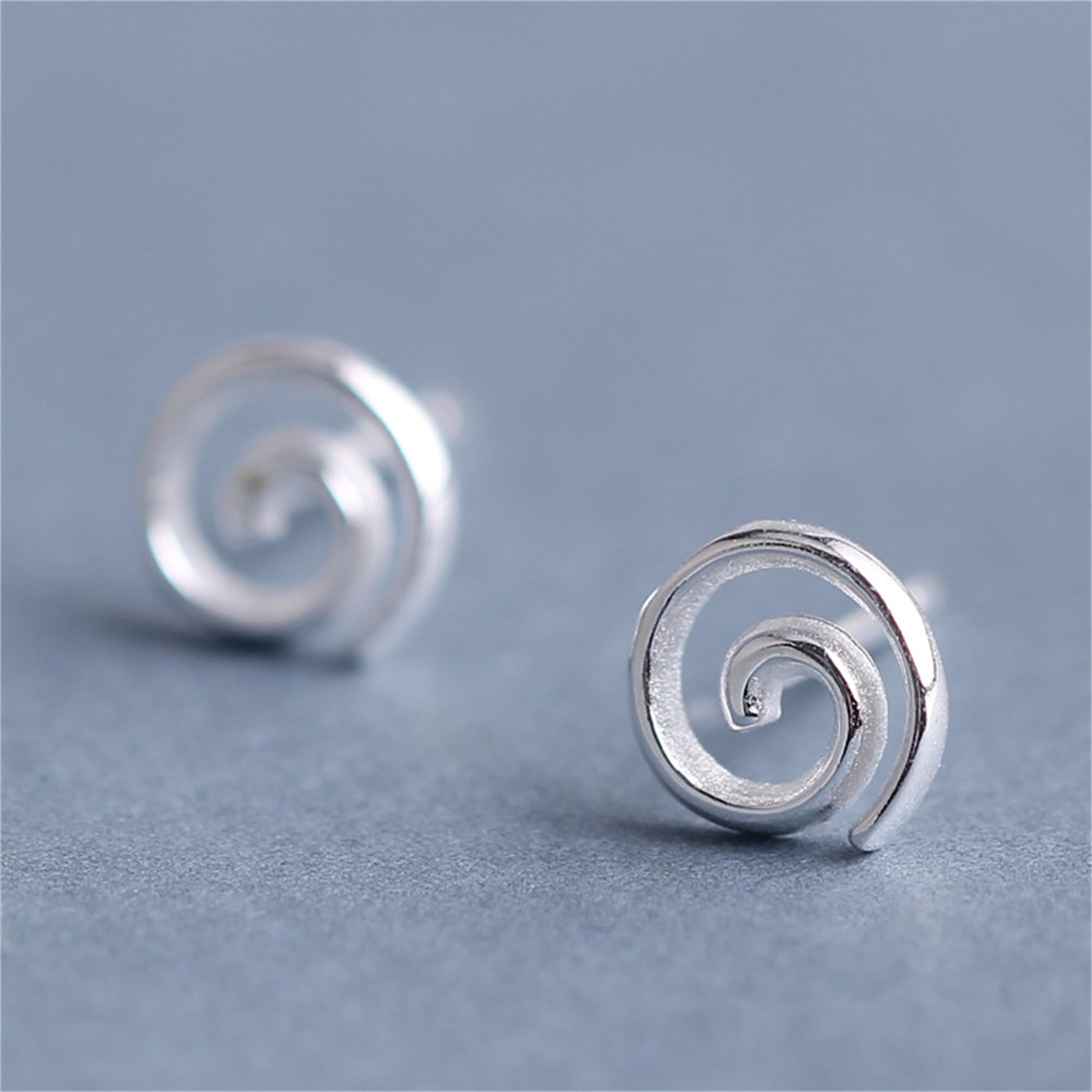 Silver spiral swirl stud earrings, close-up of round back and curled center.