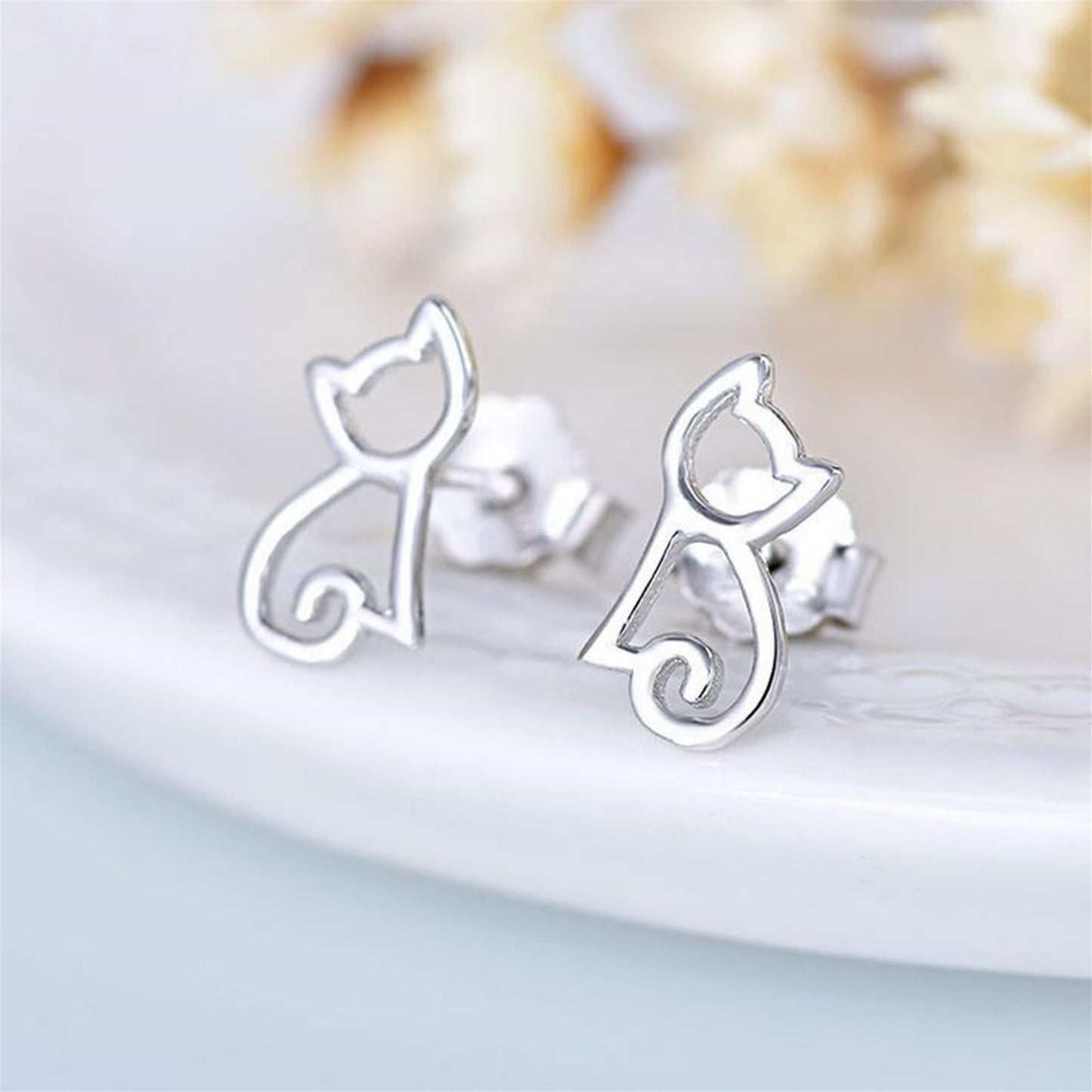 Pair of silver cat silhouette stud earrings with outline swirl tail